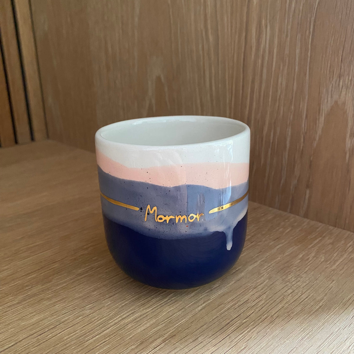 Håndlavet keramikkop med teksten Mormor i guld, blå og blush farvefelter og en synlig glasurløber på forsiden.