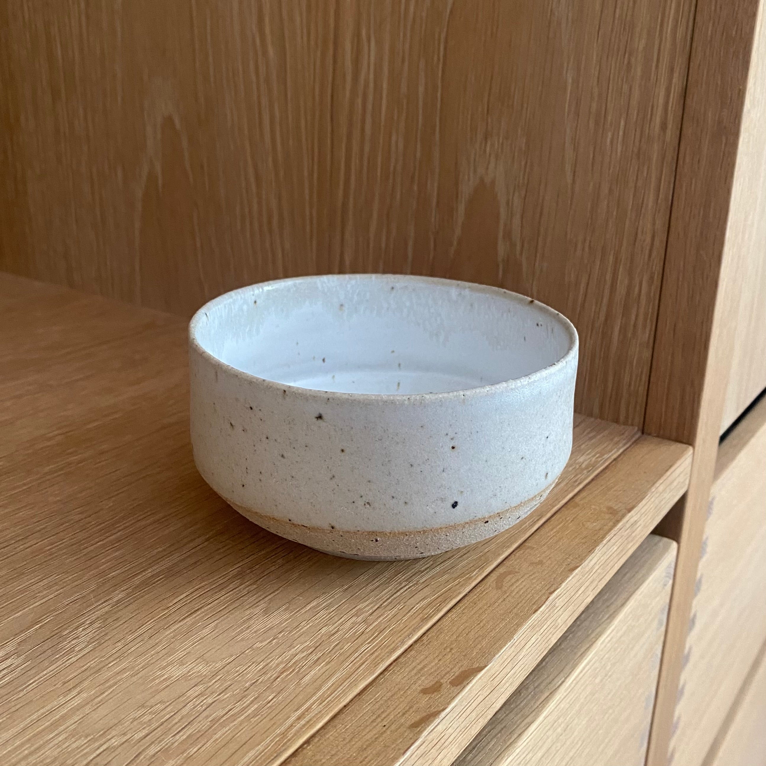 Hånddrejet matcha kop Yuki i mat hvid og sand keramik på bænk udenfor – dansk stentøj af Tasja P