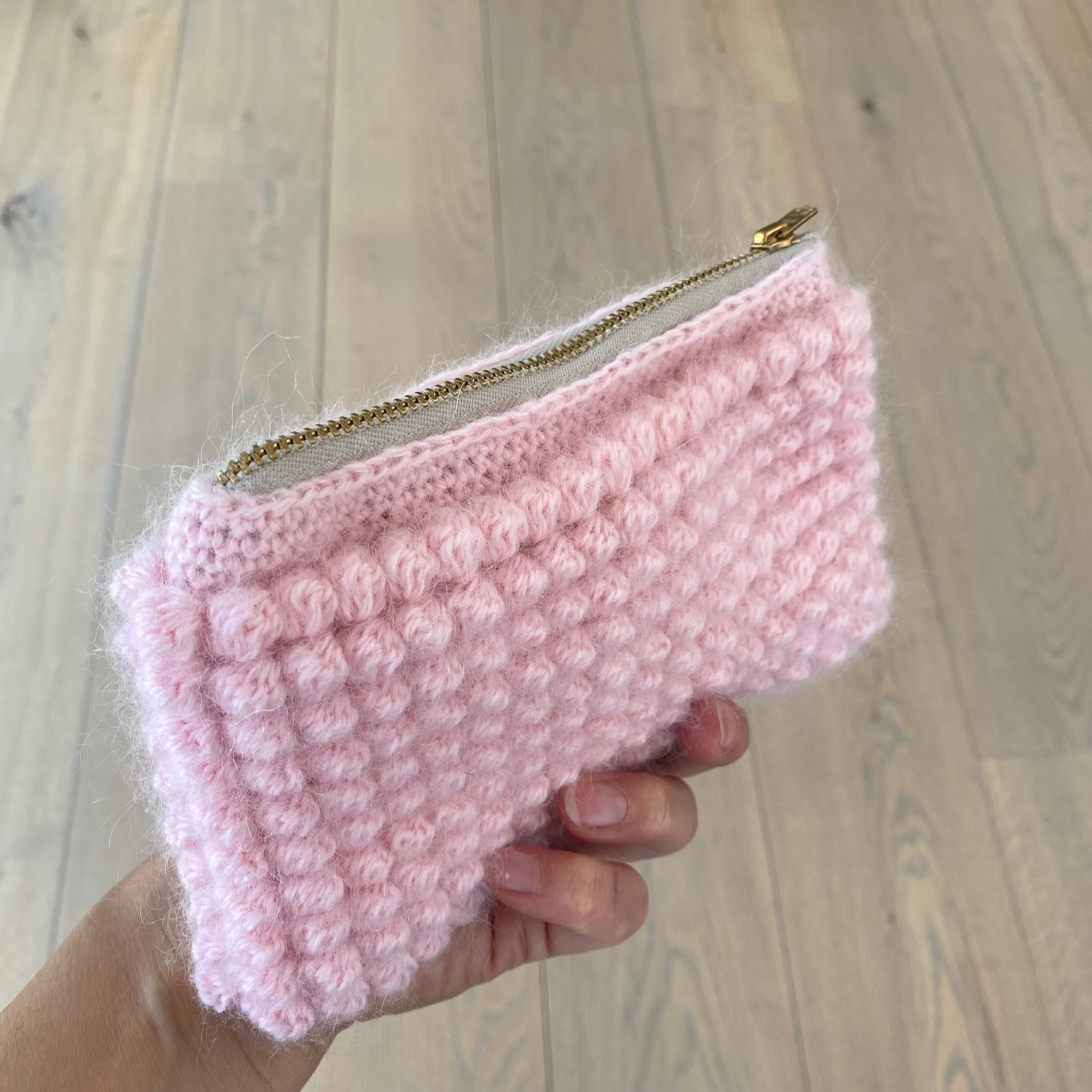 Håndhæklet lyserød clutch i bobledesign – Marie – holdt i hånden