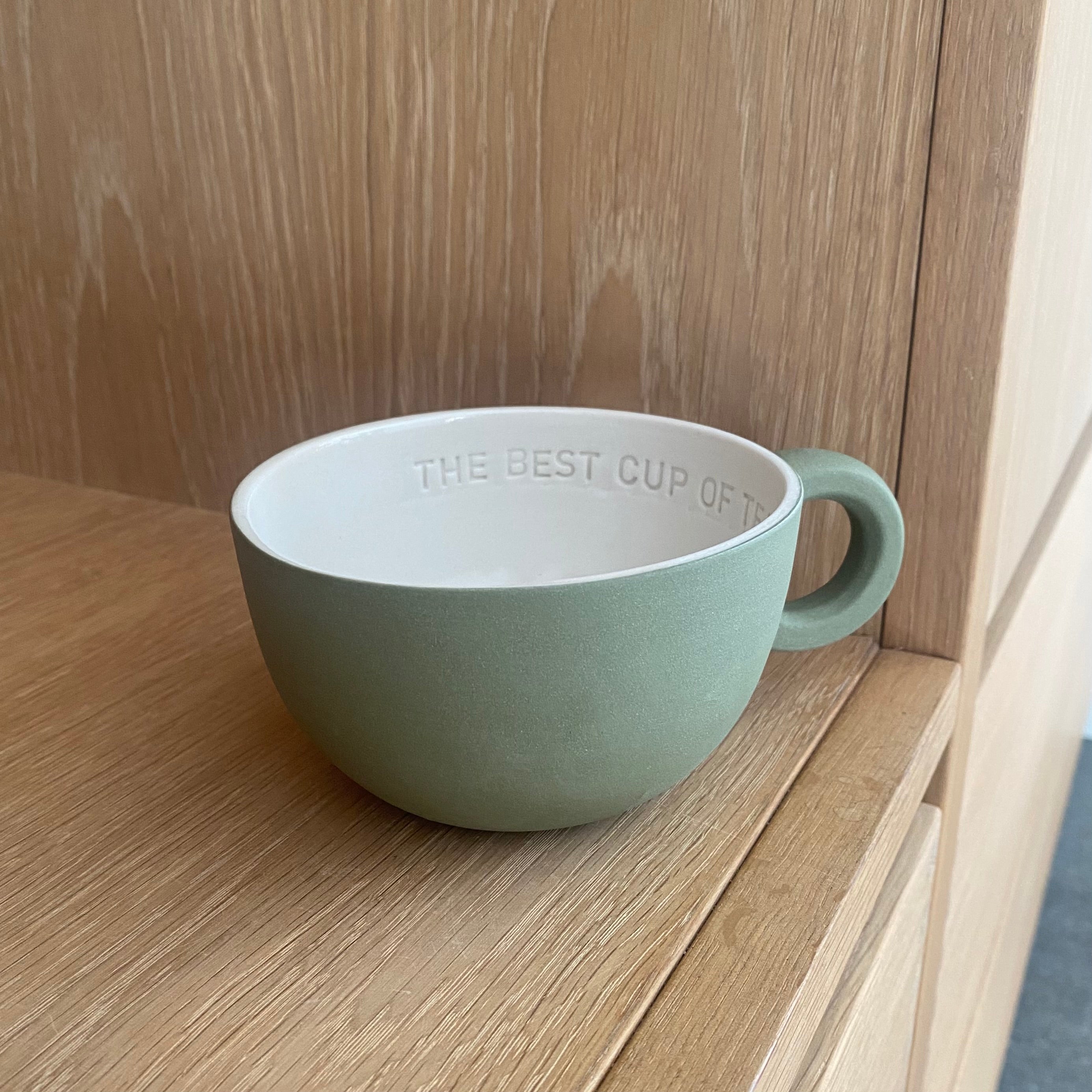 Chubby tekop i olivengrøn håndlavet keramik med hvid glasur og teksten “The best cup of tea is with you”