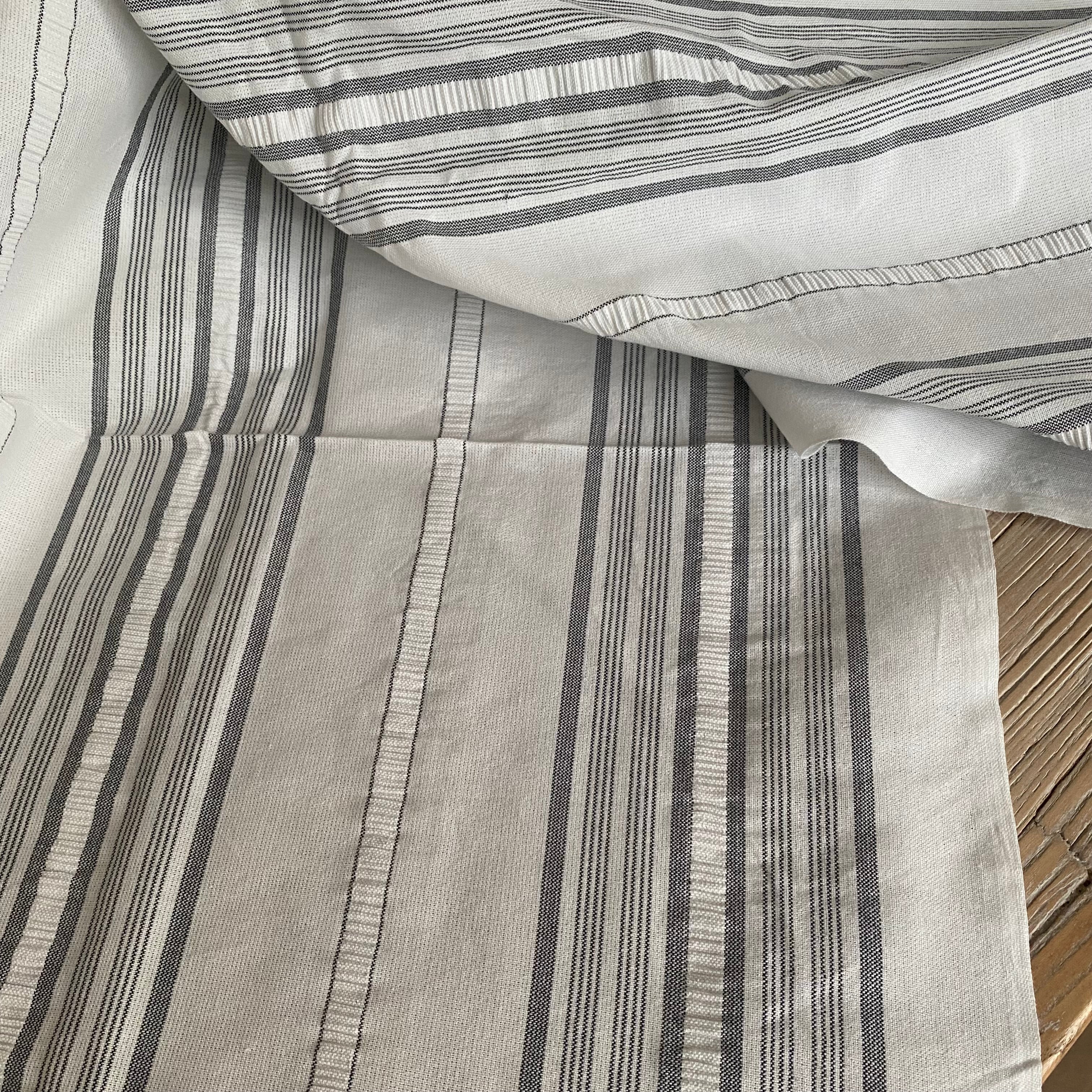 Detalje af gråsorte striber på hvid bomuldsdug