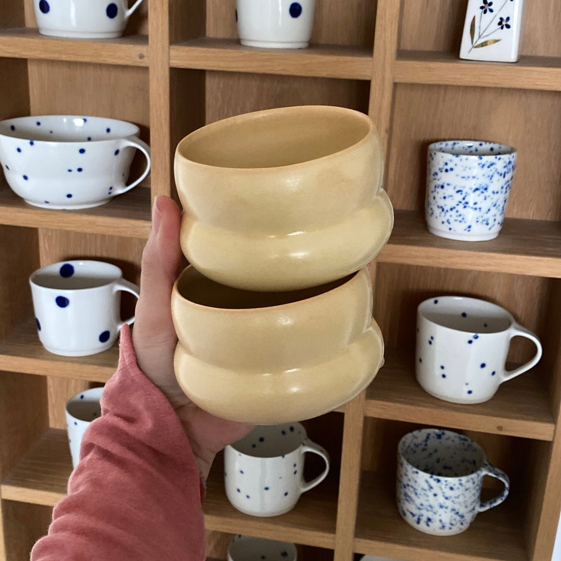 To kaffekopper IWA Wheat Yellow fra Oh Oak holdt i hånden – håndlavet keramik fra Bornholm hos unika:k