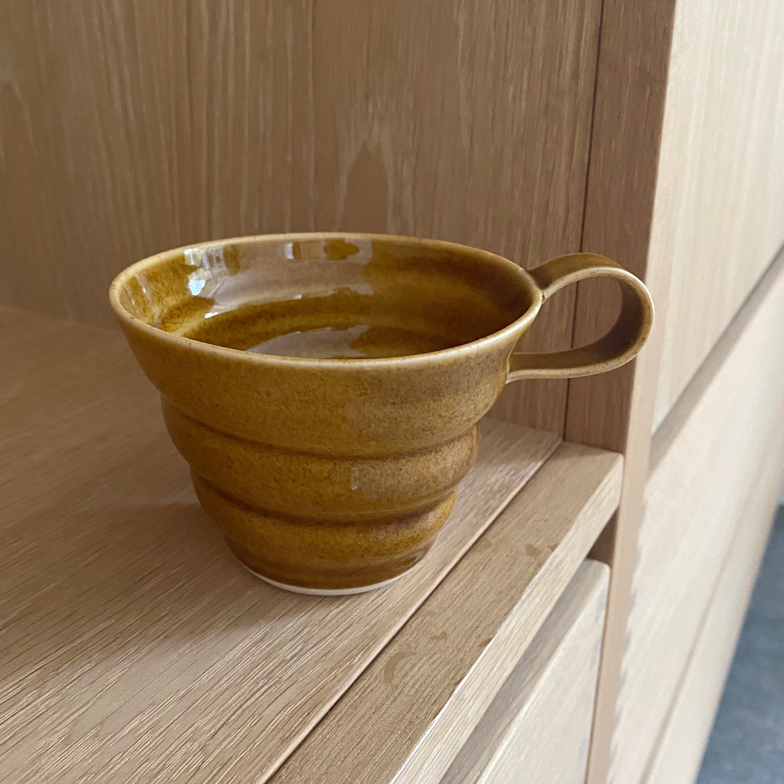 keramikkop kop med hank lavet af rikke mangelsen i gyldenbrun glasur