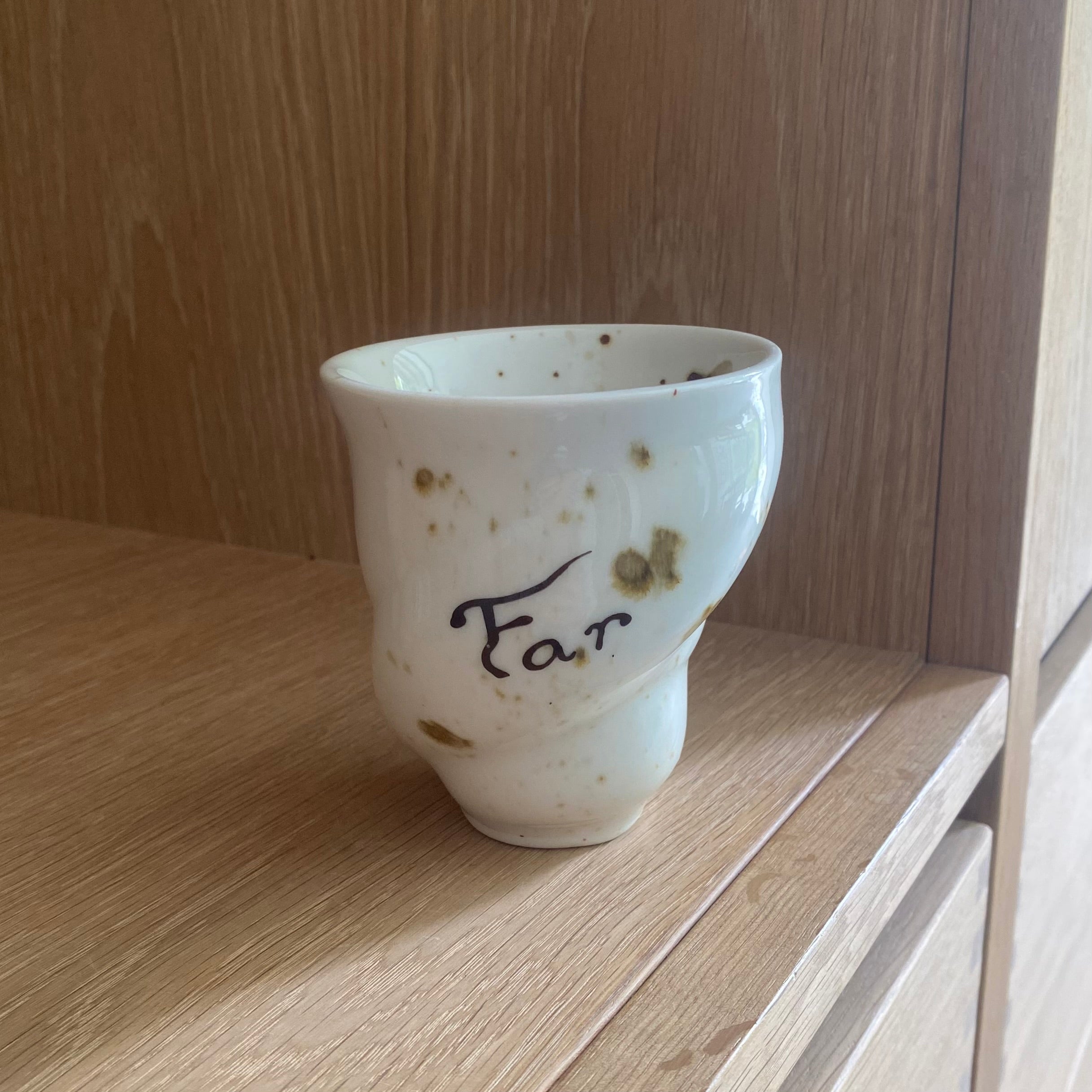 Håndlavet keramikkop med FAR-tekst fra Studio Aarhus – stående på træbord i naturligt lys