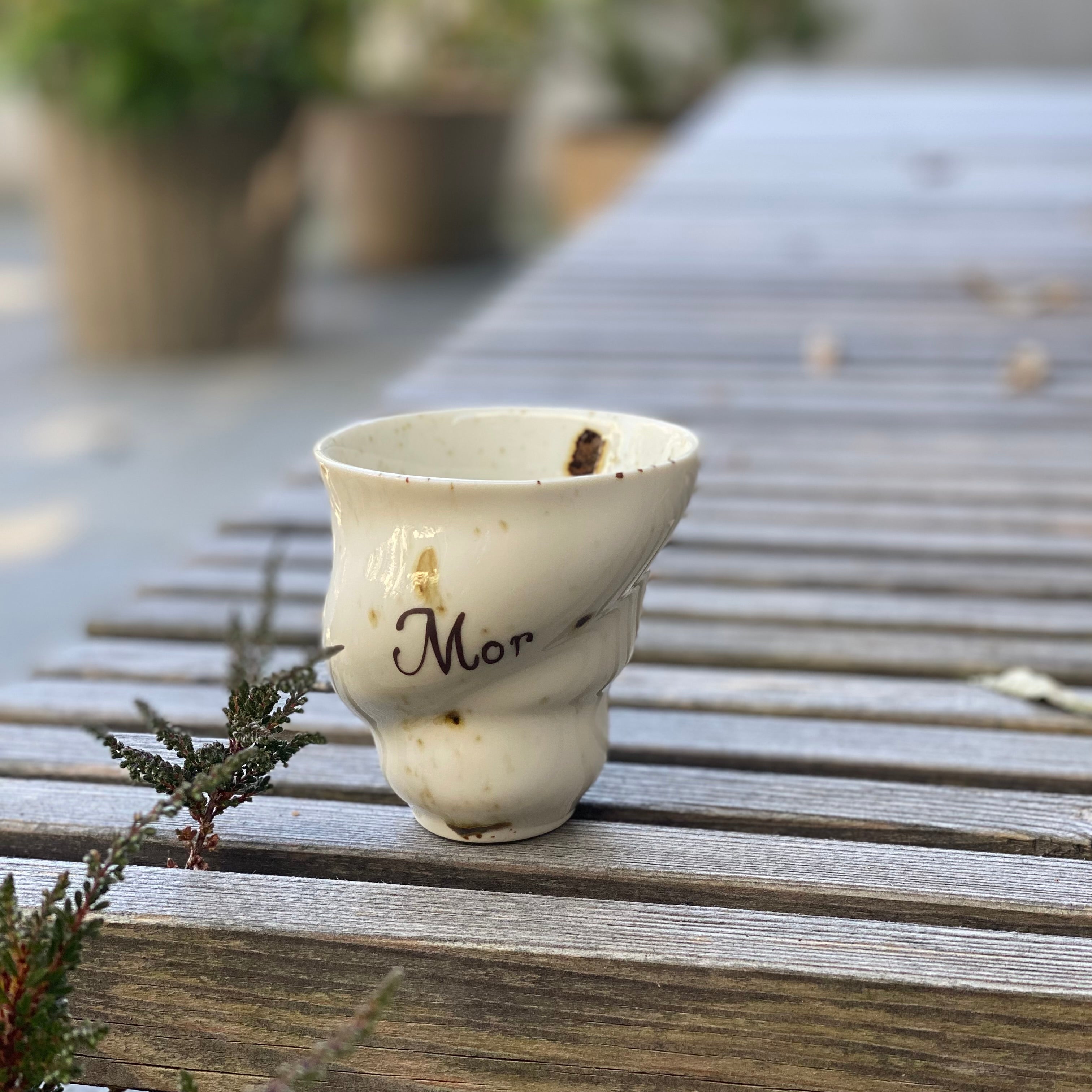 Håndlavet keramikkop “Mor” fra Studio Aarhus i hvid og mørkebrun glasur – står på bord