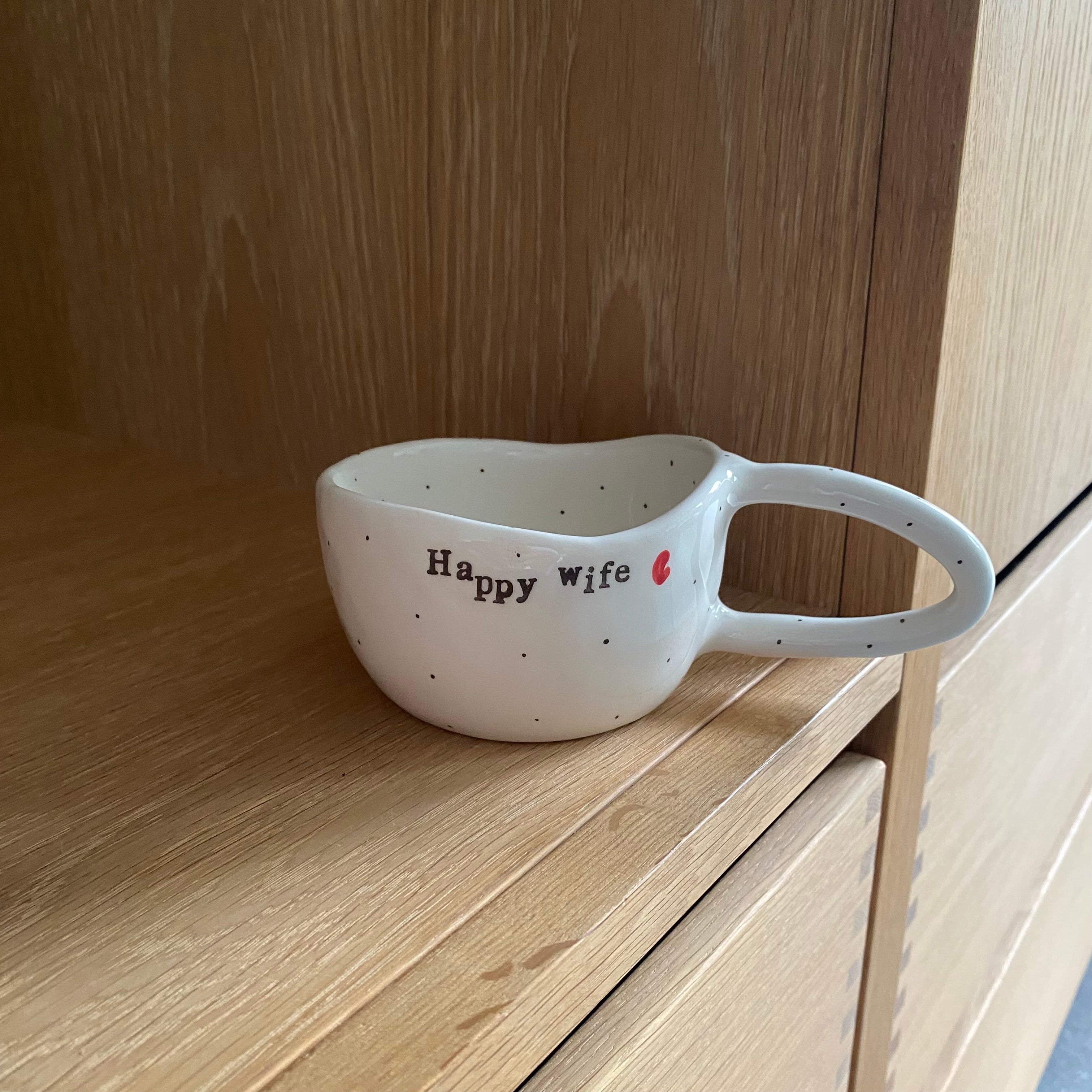 Håndlavet kop med hank og teksten “Happy wife, Happy life” i hvid keramik med sorte prikker