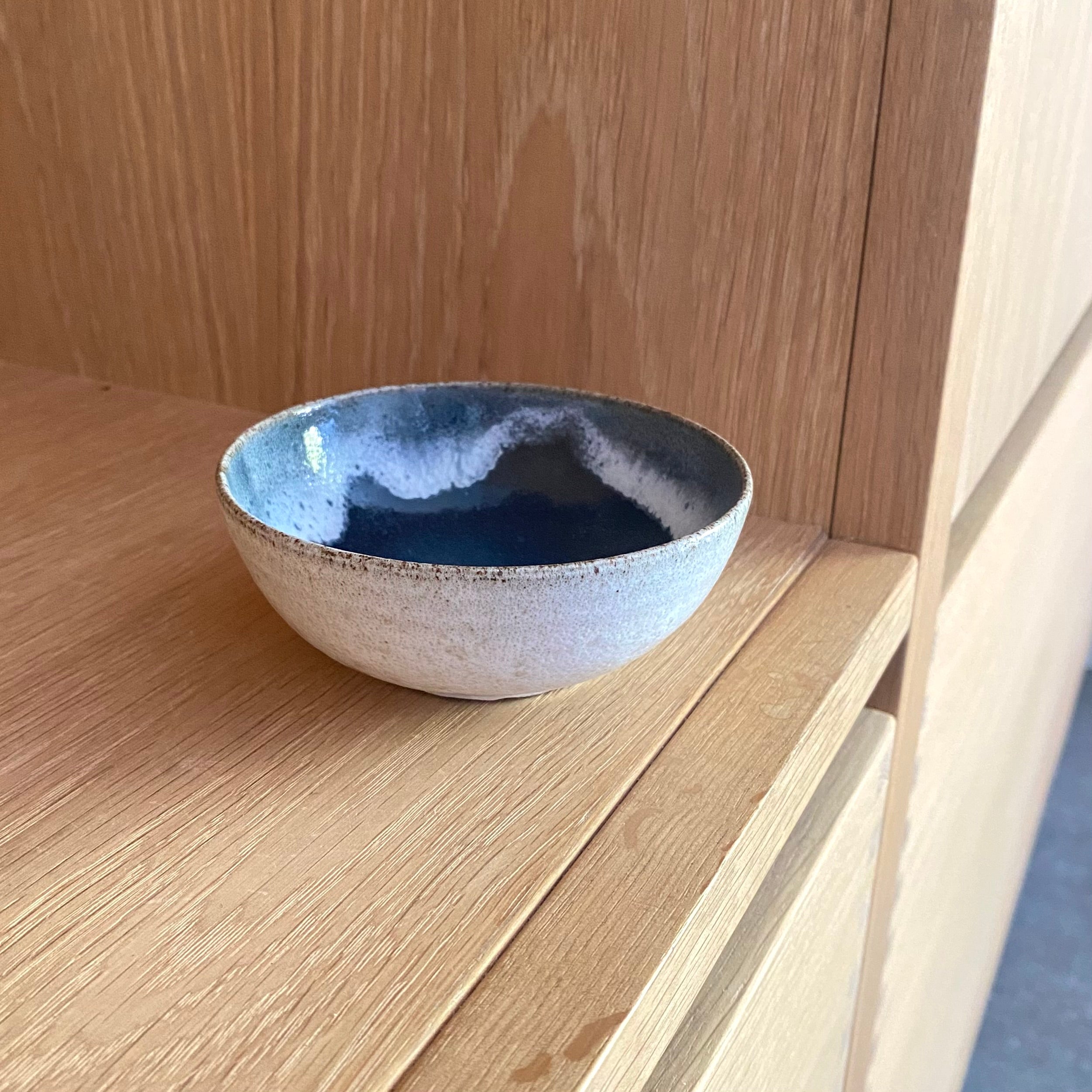 Hånddrejet keramikskål i rustikt stentøj – blå glasur der løber