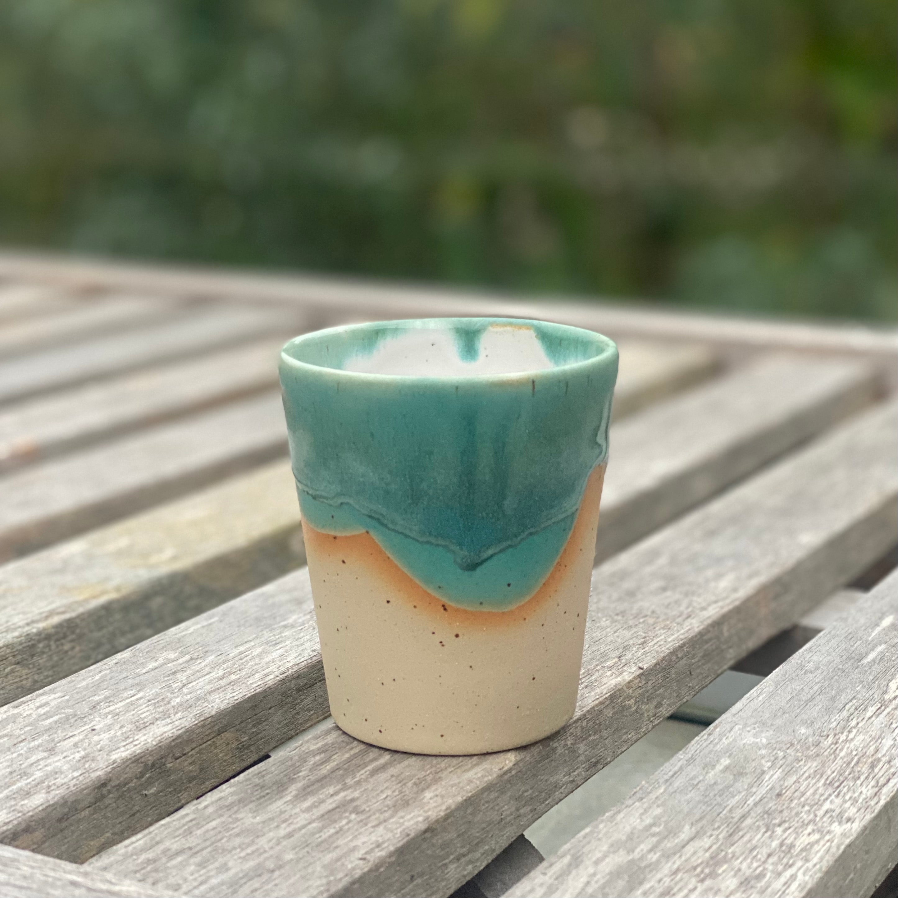 Hånddrejet flat white kop fra Marinski Heartmades i grøn glasur og naturfarvet stentøj – set på bord