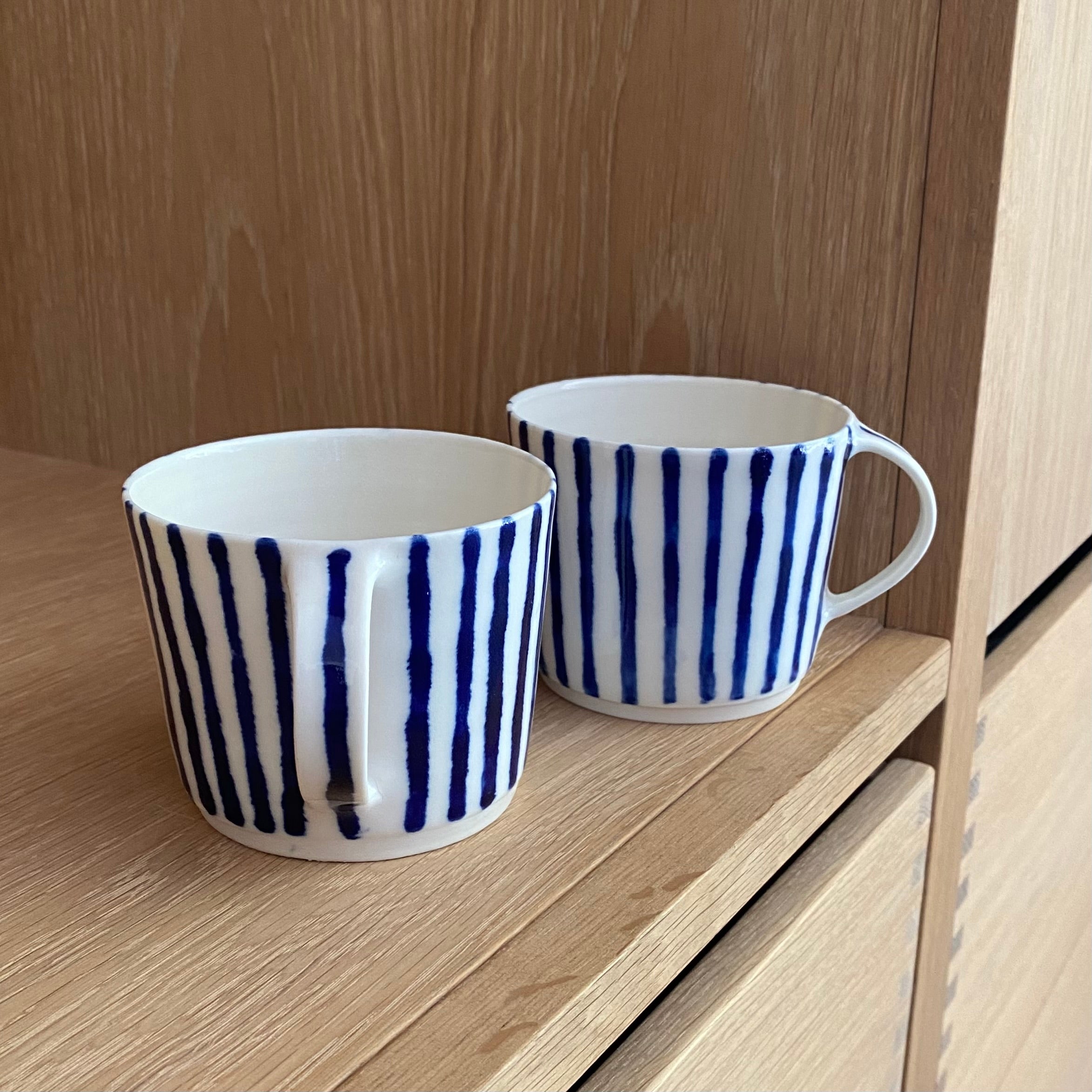 Nærbillede af håndlavet porcelænskop med blå striber og hank