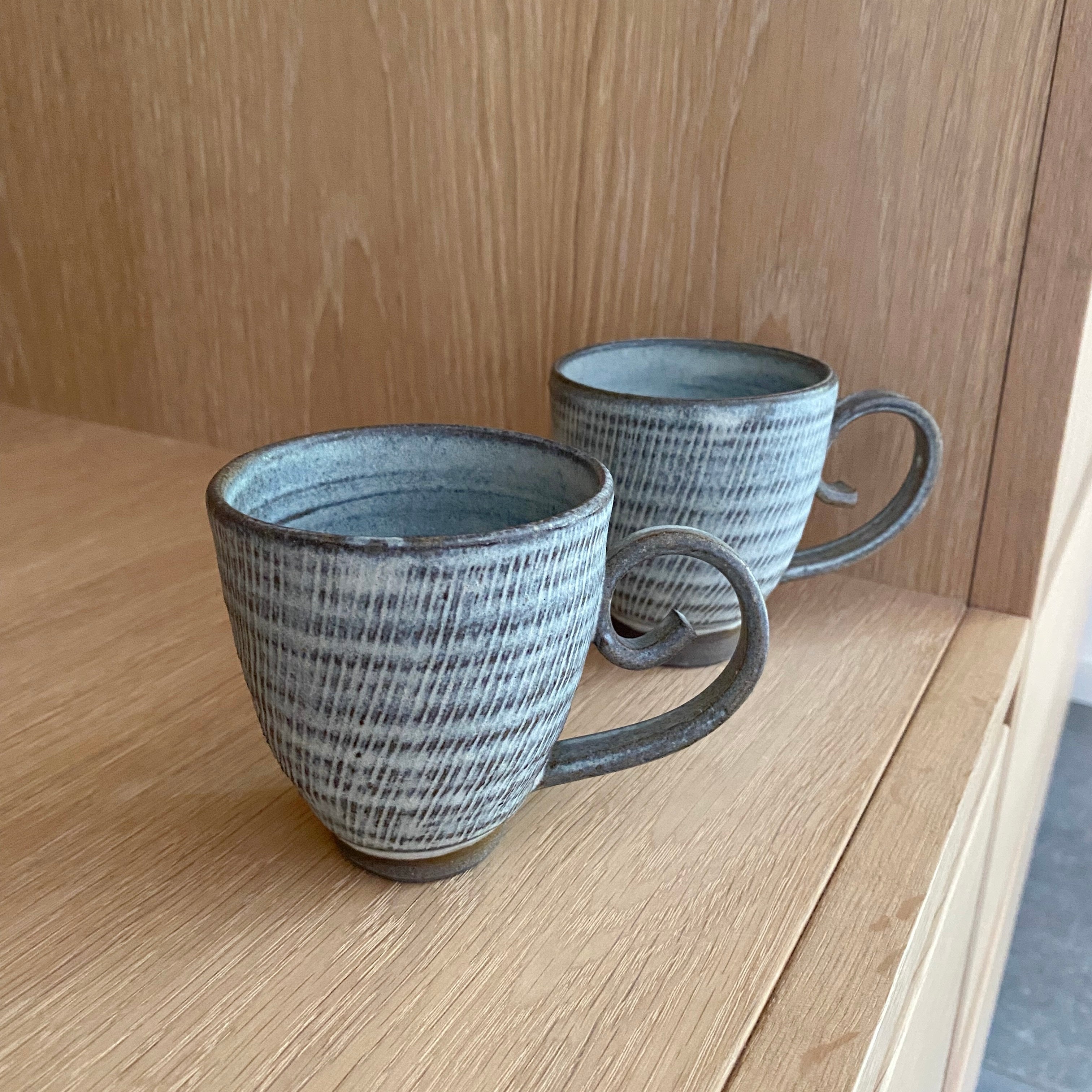 Riflet keramikkop med hjerteformet hank i støvet blåbrun farve