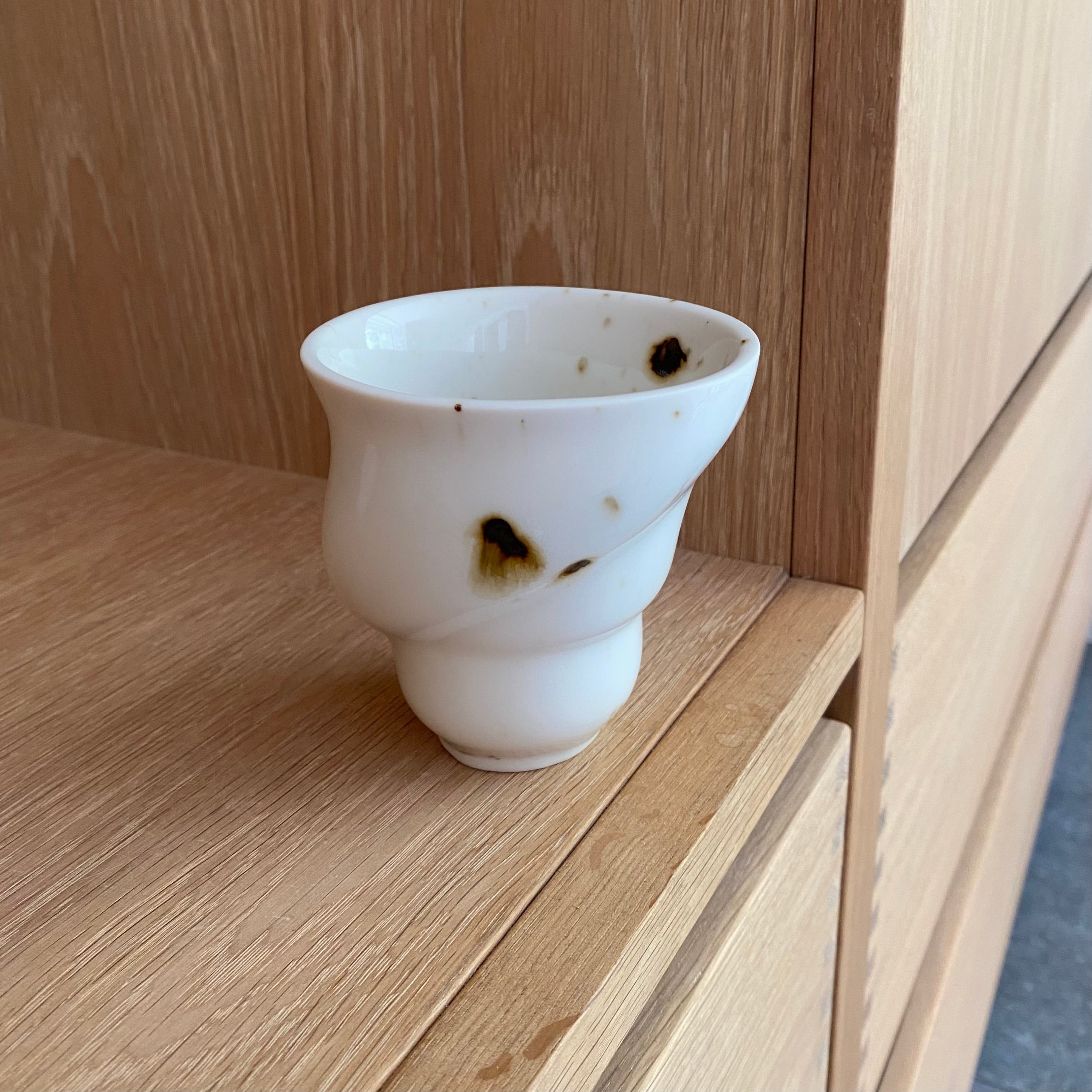Ryle keramikkop i sort og hvid stående på bord – håndlavet kaffekop i porcelæn fra Studio Aarhus