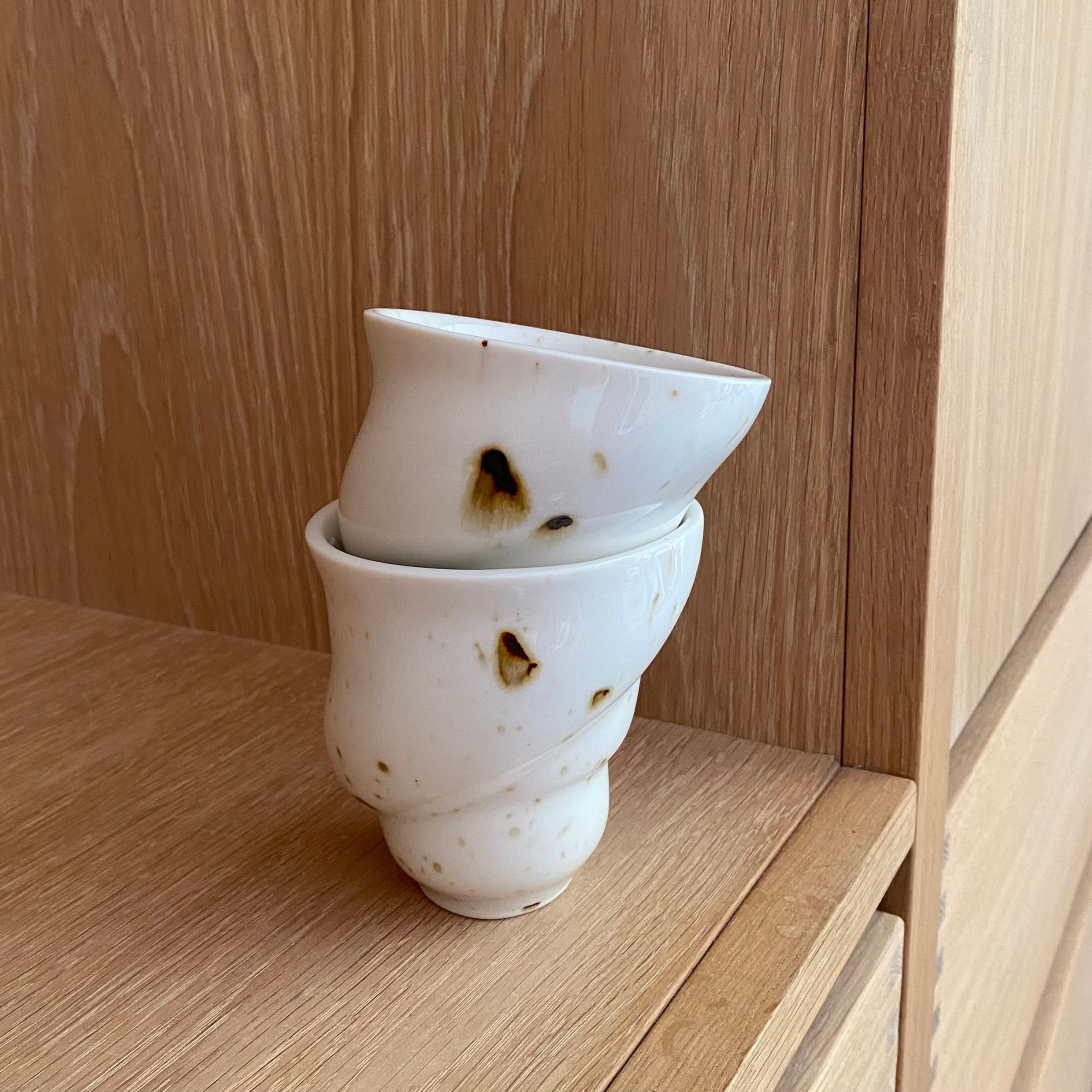 Flere håndlavede Ryle keramikkopper på hylde – sort-hvid porcelæn i nordisk design