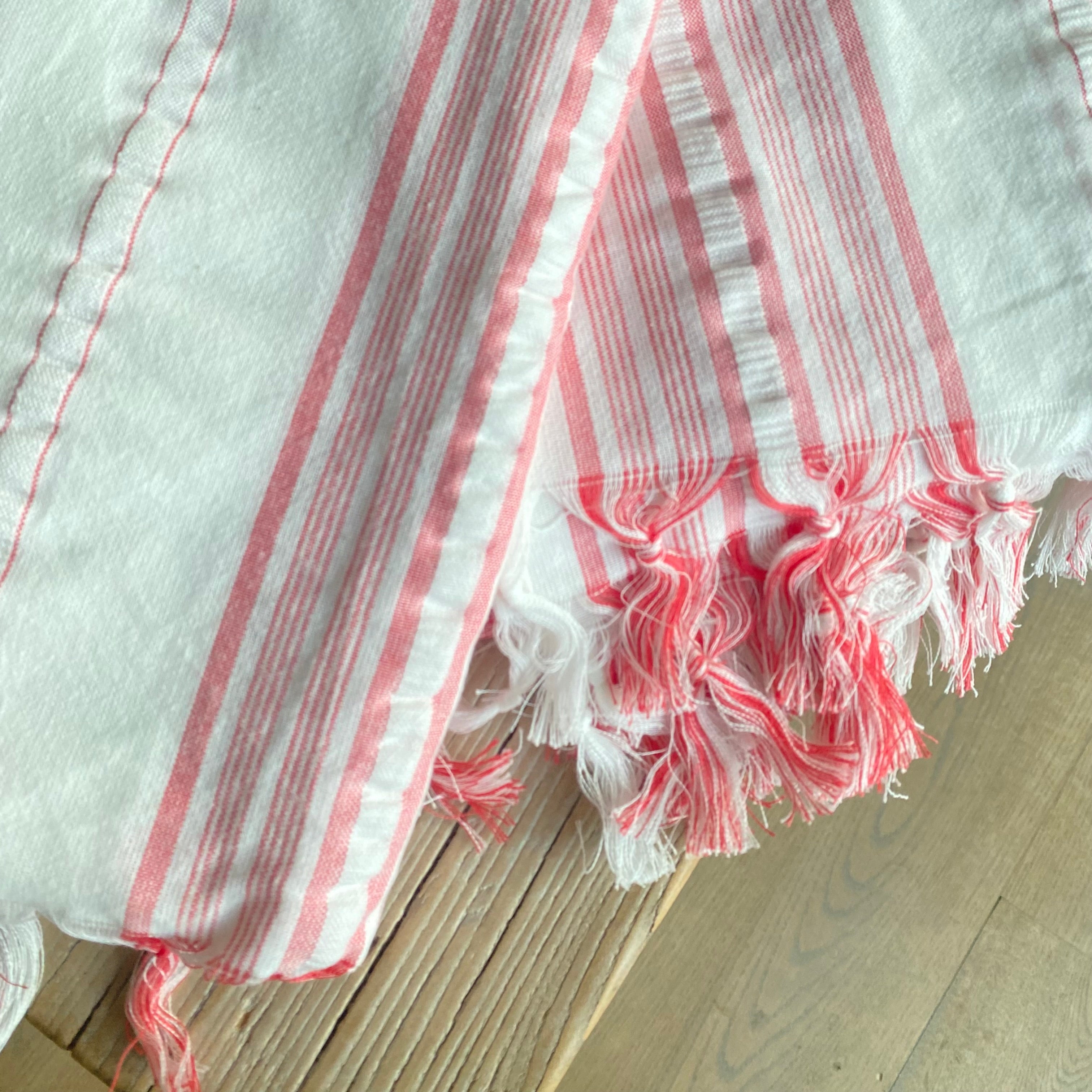 Styling af hvid dug med koralrøde striber på spisebord