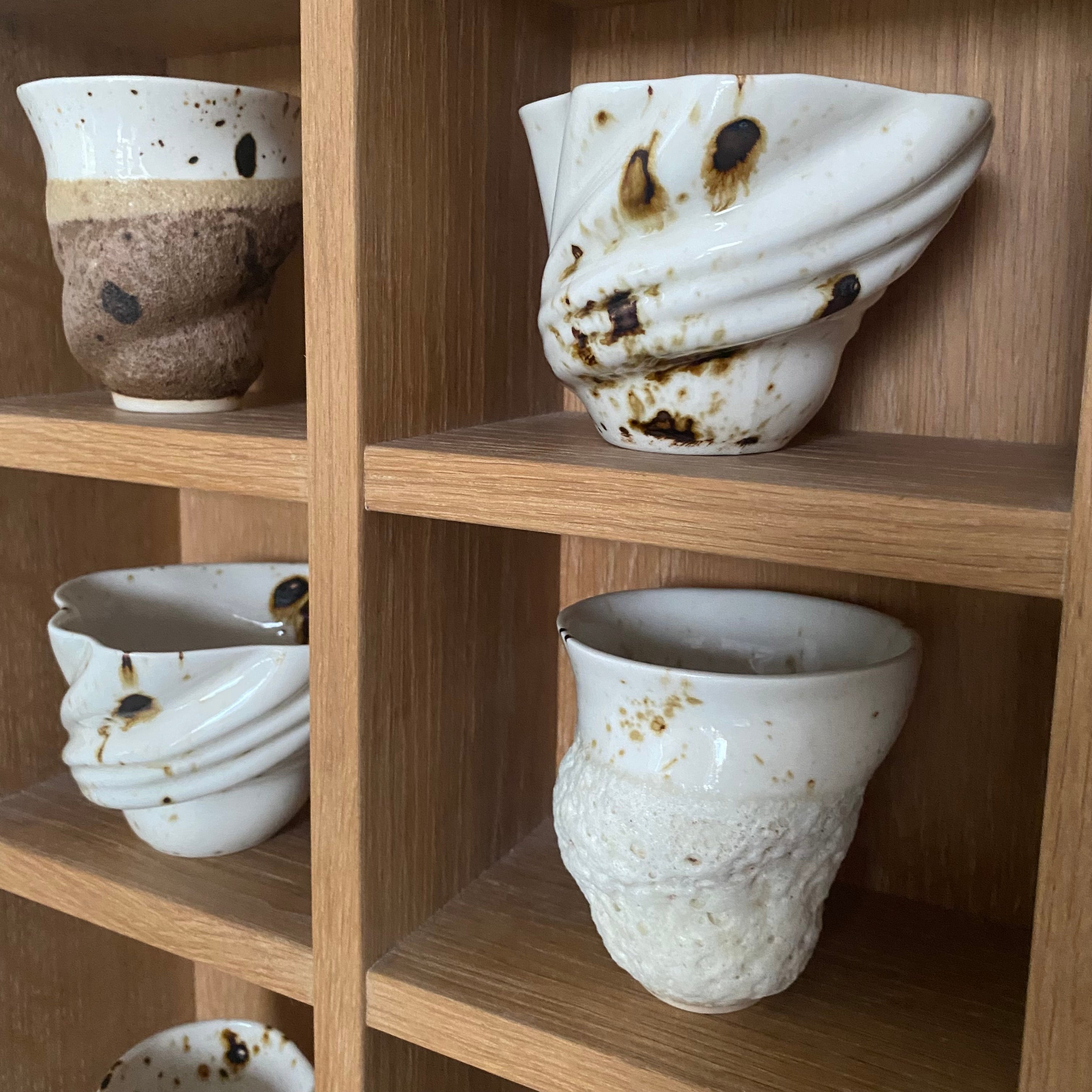 Række af håndlavede svanekopper udstillet på hylde – unika keramik fra Studio Aarhus