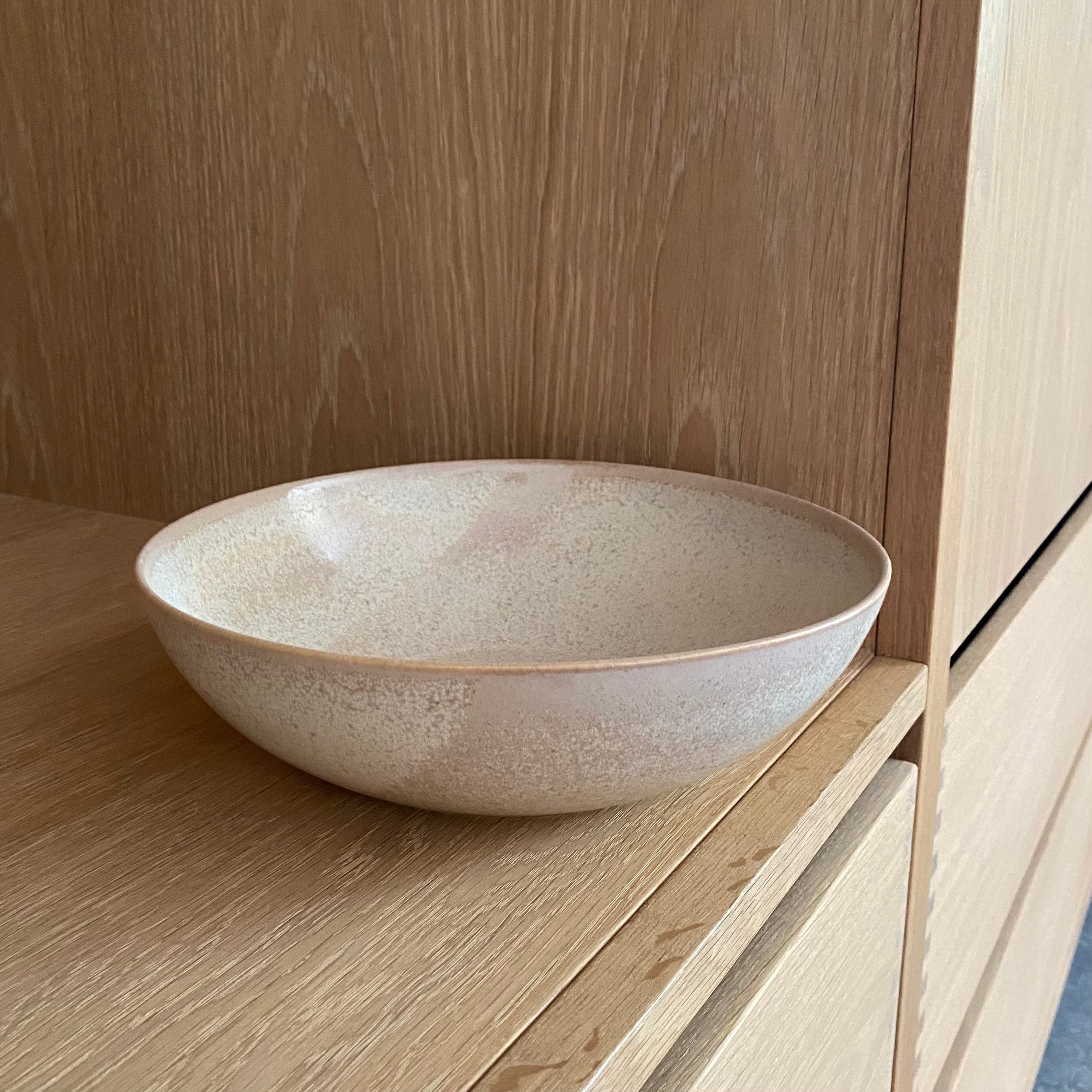 Håndlavet keramiksalatskål Tone Golden på bord – stor dansk keramikskål i gylden glasur fra Wauw Design