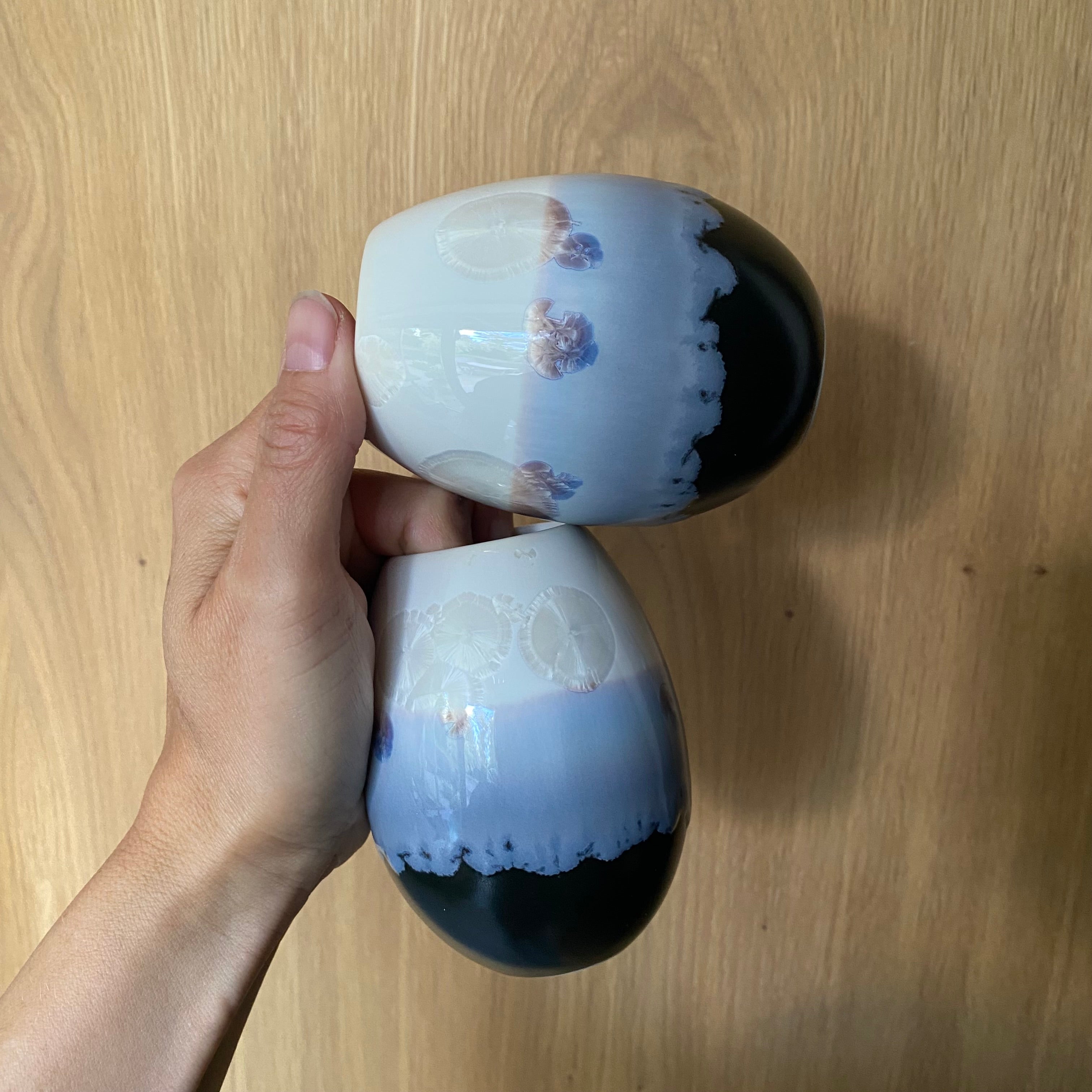 To Crystal vaser i hvid og lyseblå holdt i hånden – håndlavet porcelæn med krystalglasur fra Wauw Design