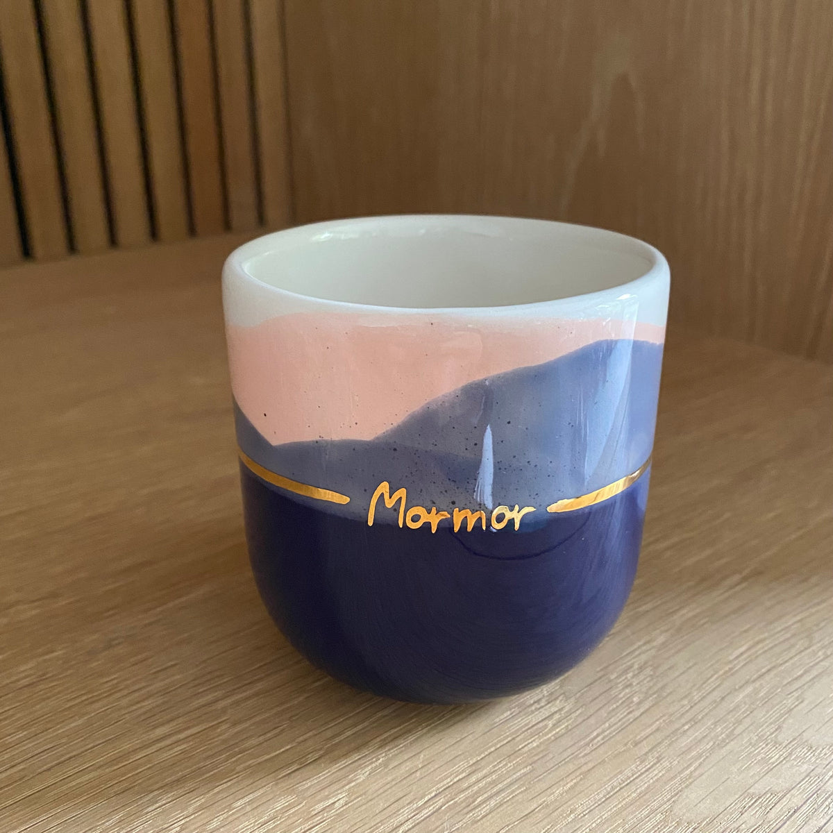 Mormor kop i håndlavet keramik med kongeblå og blush glasur samt håndskrevet guldtekst og guldbånd på en træhylde.