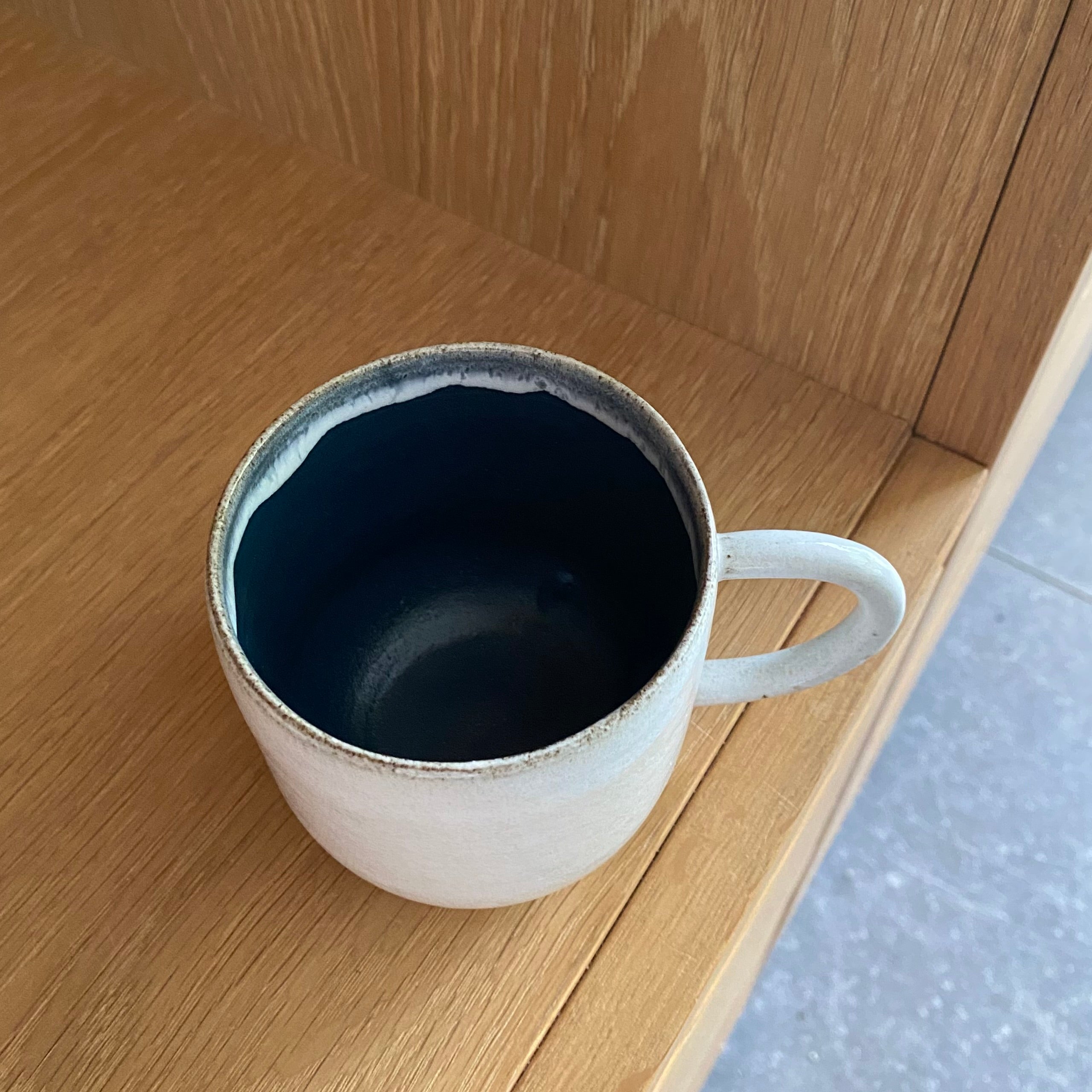 Kaffekop med hank i mørkeblå keramik set fra siden – hånddrejet dansk keramik med mørkeblå glasur indeni