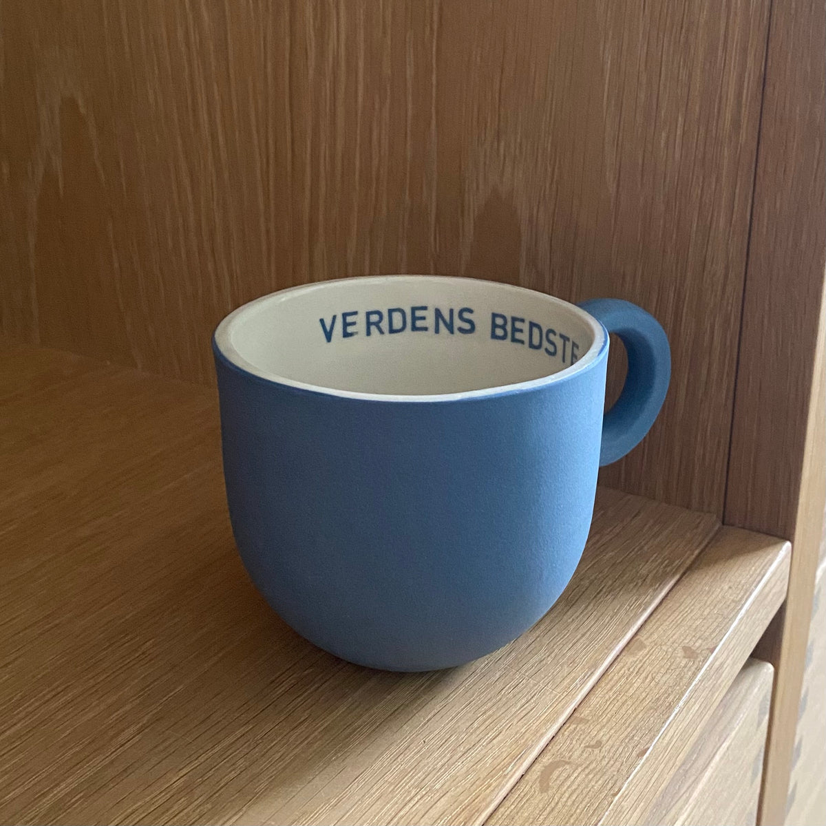 Dansk keramik – oceanblå kop til morfar med rund hank til højre og teksten Verdens bedste synlig indeni.