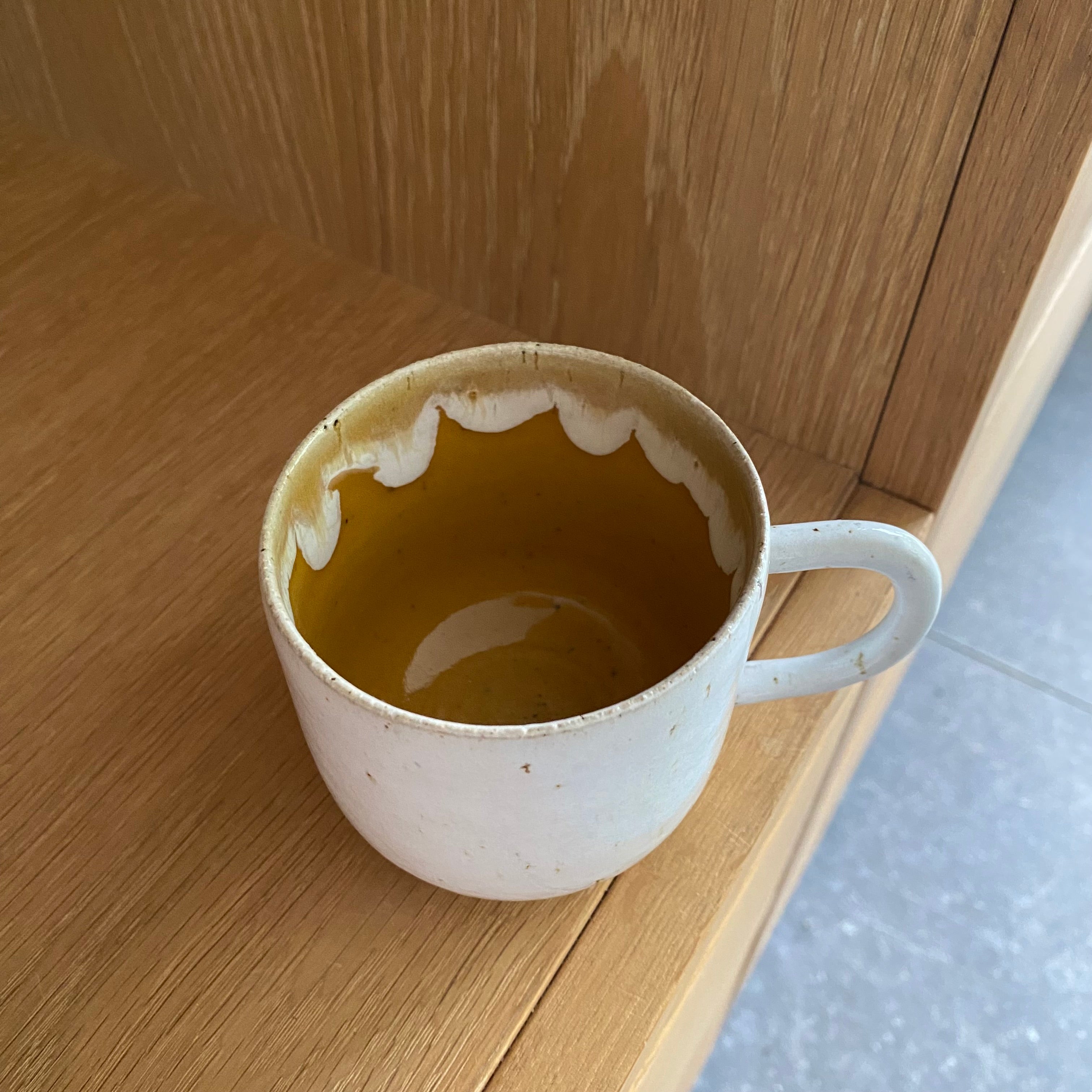 Kaffekop med hank i gul keramik set fra siden – hånddrejet dansk keramik med gul glasur indeni