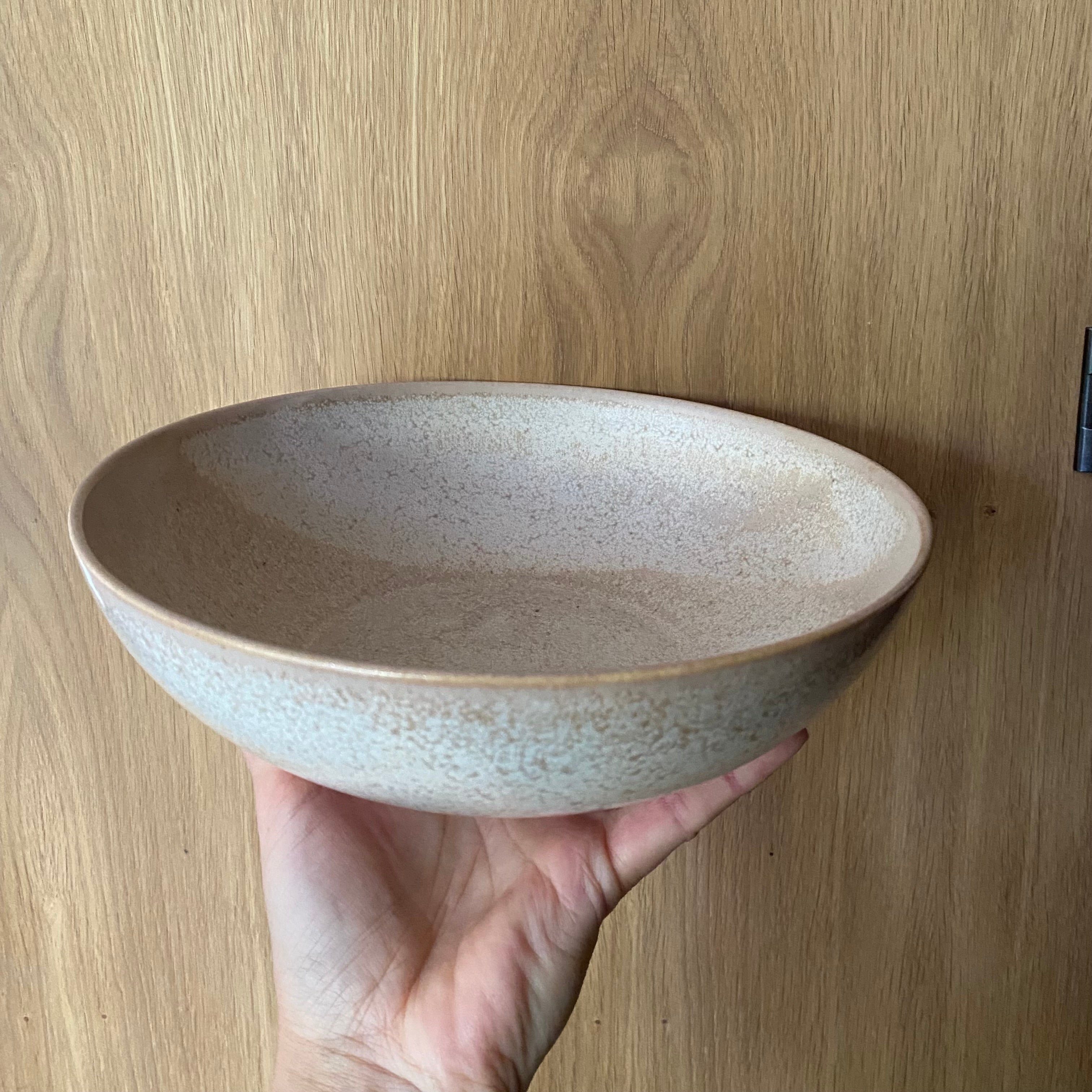 Salatskål Tone Golden holdt i hånden – håndstøbt porcelæn i unik golden glasur fra Wauw Design