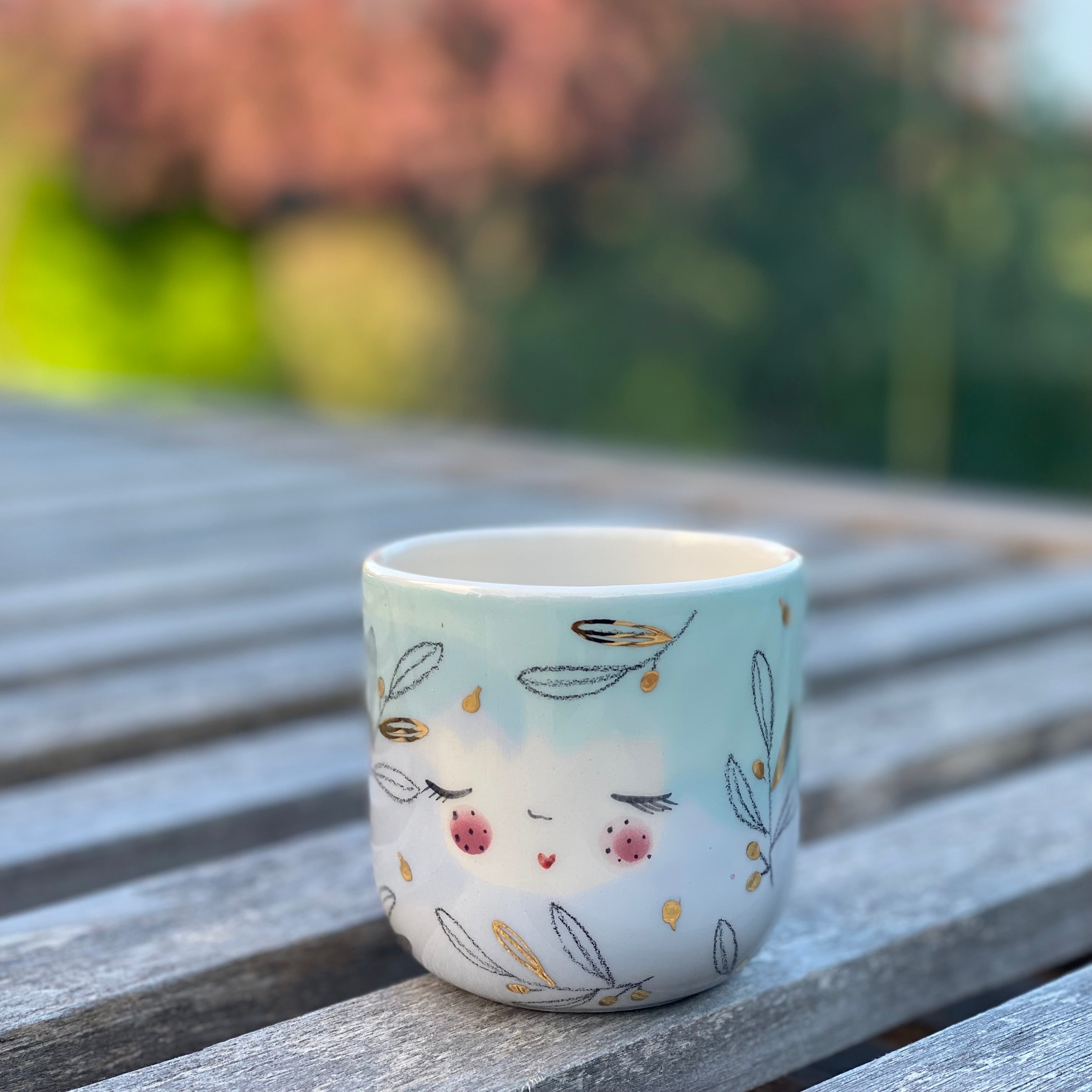 Håndlavet cappuccinokop i keramik – lyseblå og lysegrøn glasur med guld og håndtegnet ansigt – Marinski Heartmades