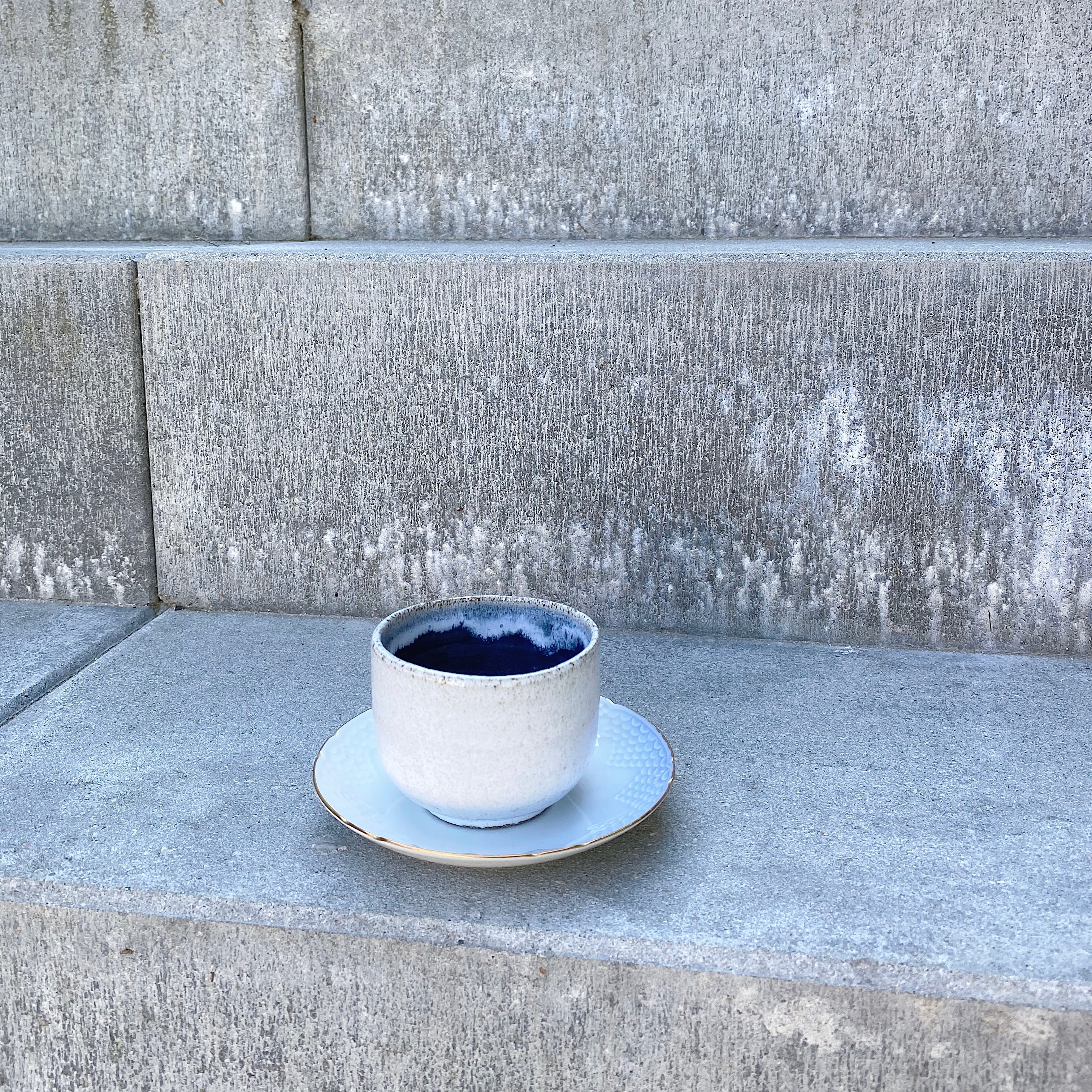 Mørkeblå espressokop i hånddrejet stentøj på trappe udenfor – unika dansk keramik