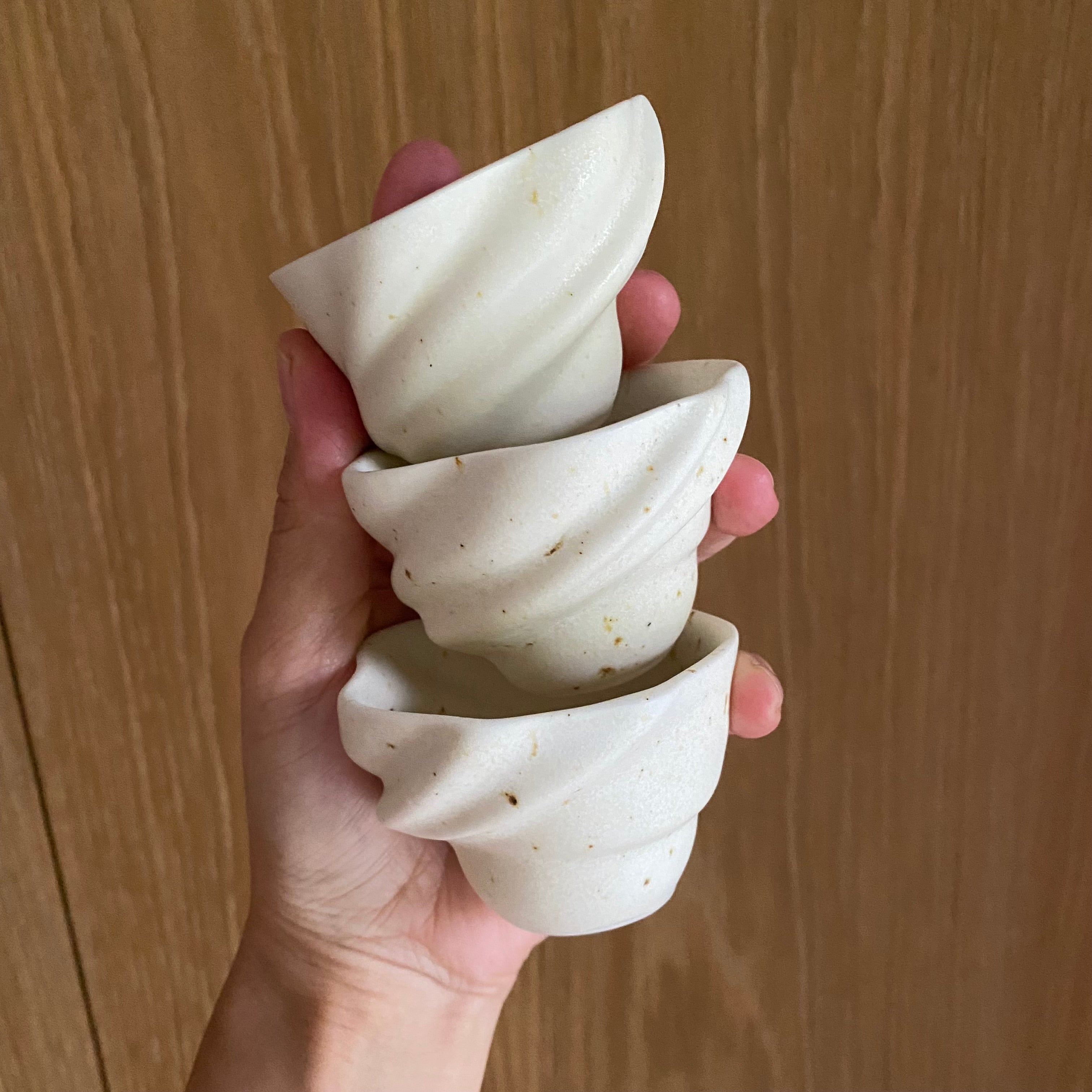 Tre håndlavede espressokopper ‘Skal’ i hvid og brun – holdt i hånden