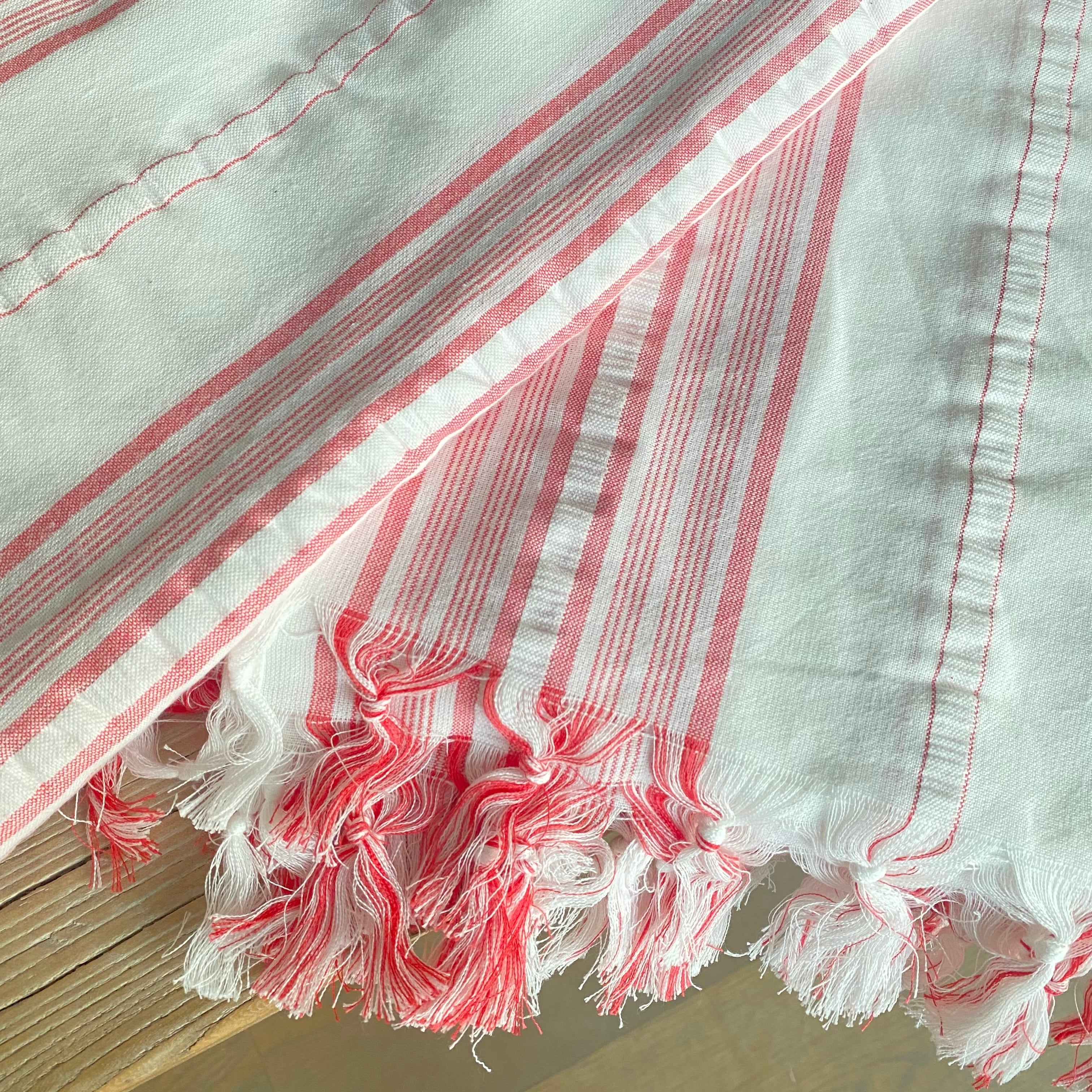 Håndknyttede frynser på hvid dug med koralrøde striber