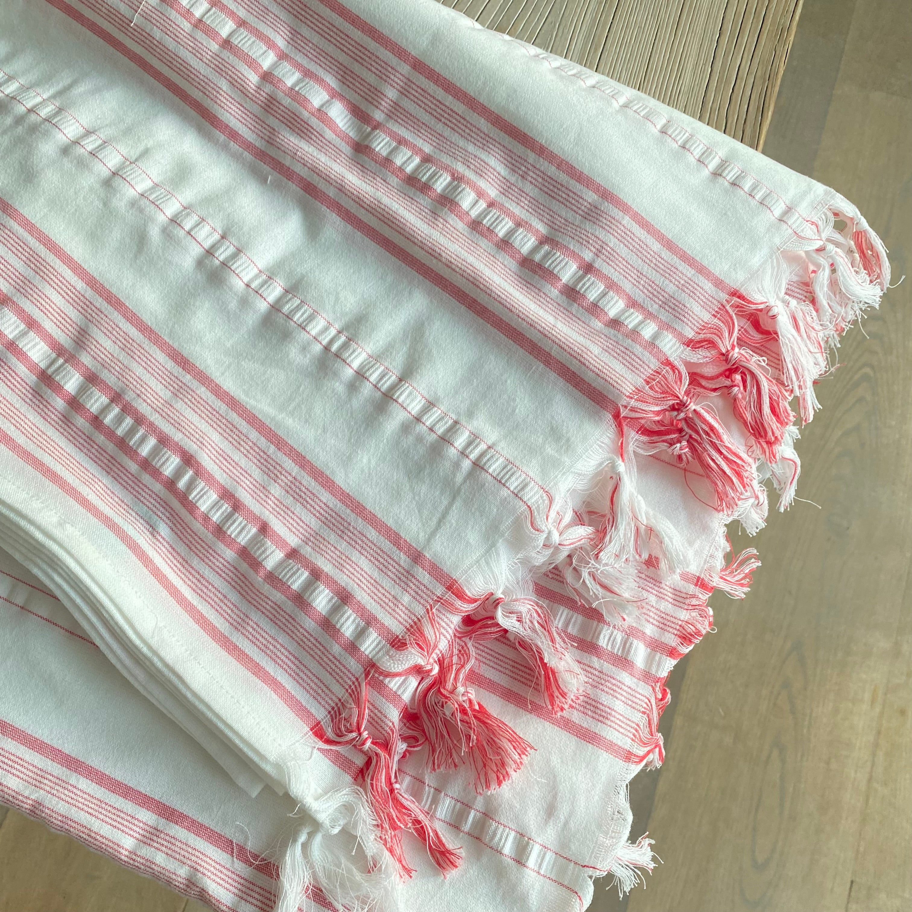 Detalje af koralrøde striber på håndvævet hvid dug