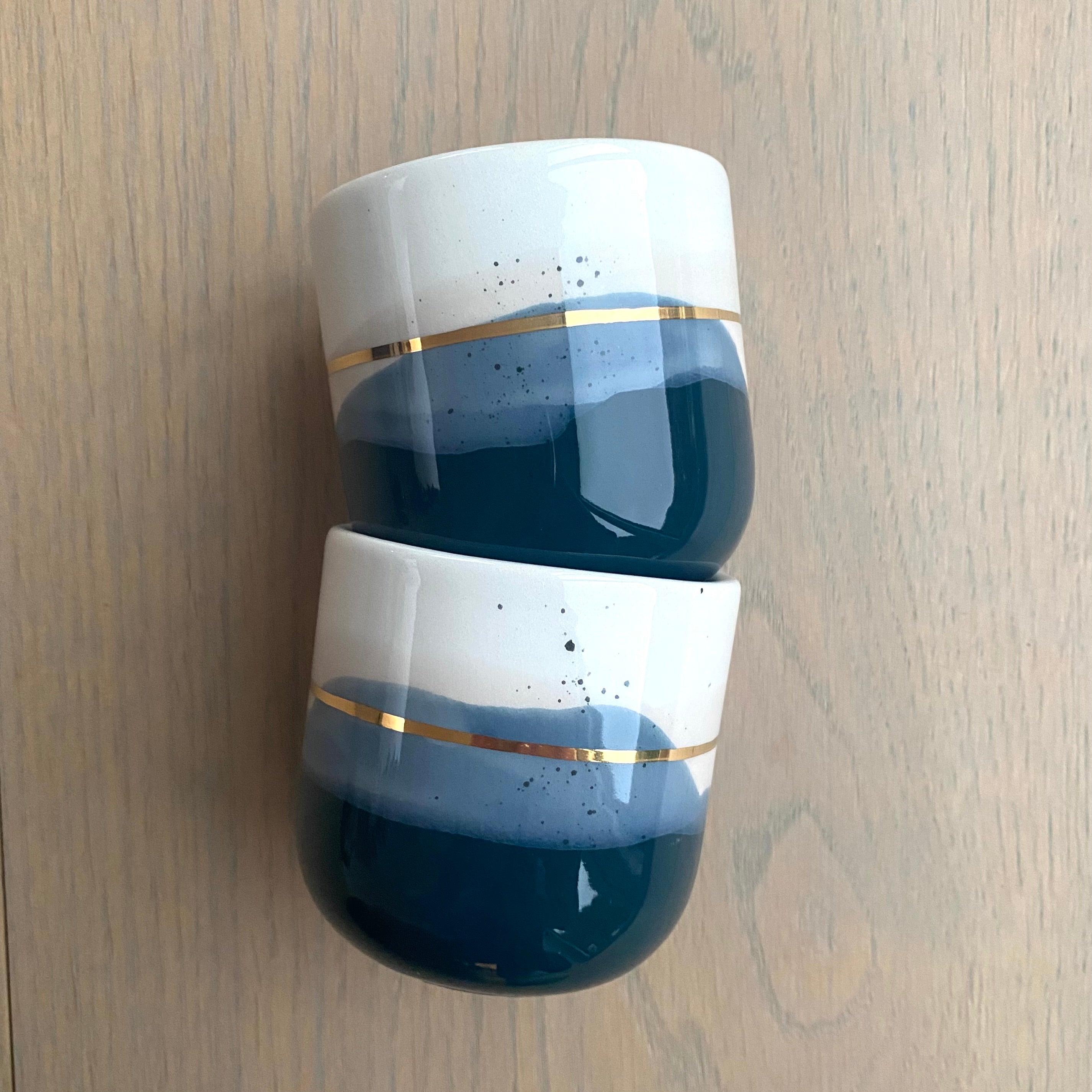 Sidevisning af unik keramikkop – blå og creme farver med guldstribe