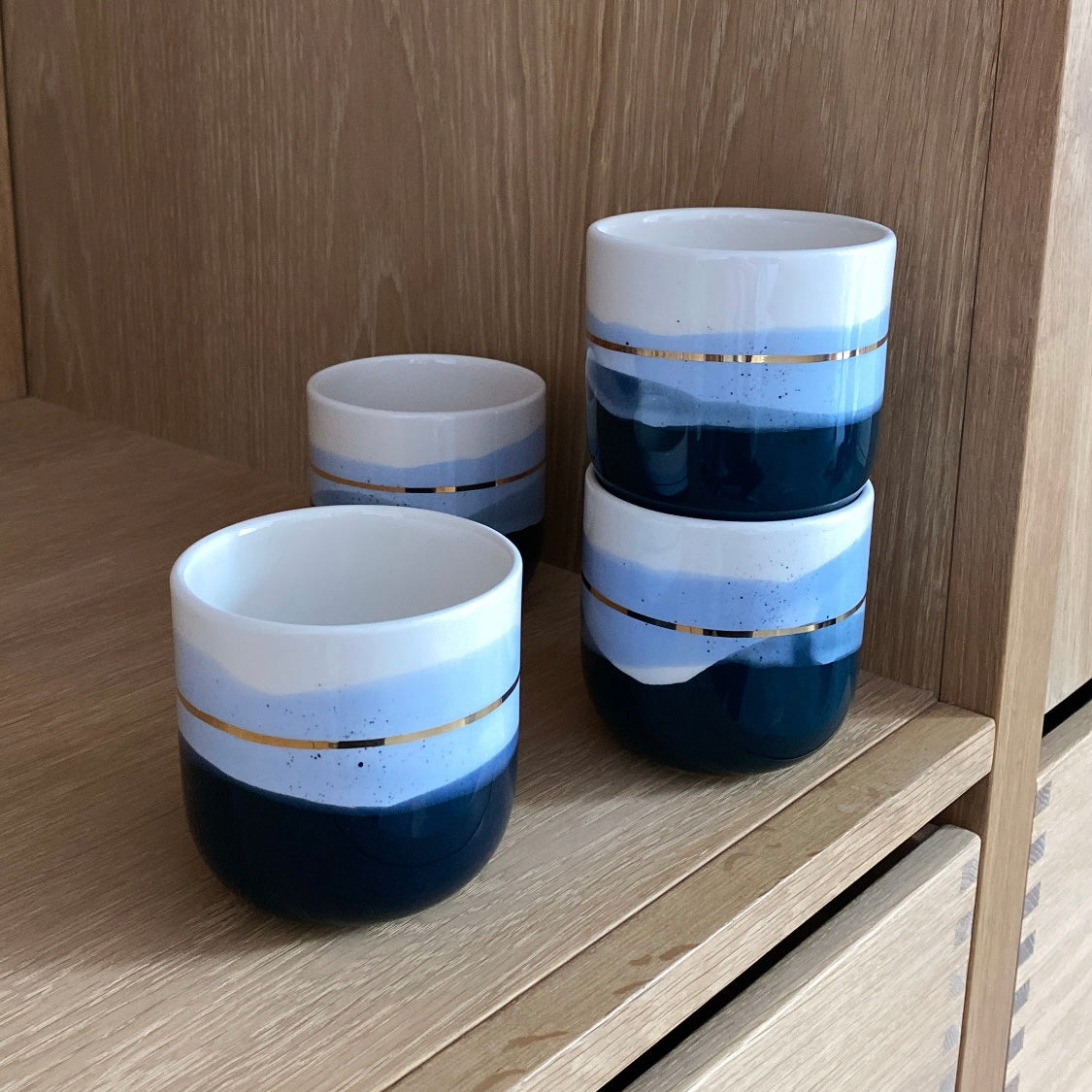 Håndlavet keramikkop med blå nuancer og guld – perfekt som personlig gave