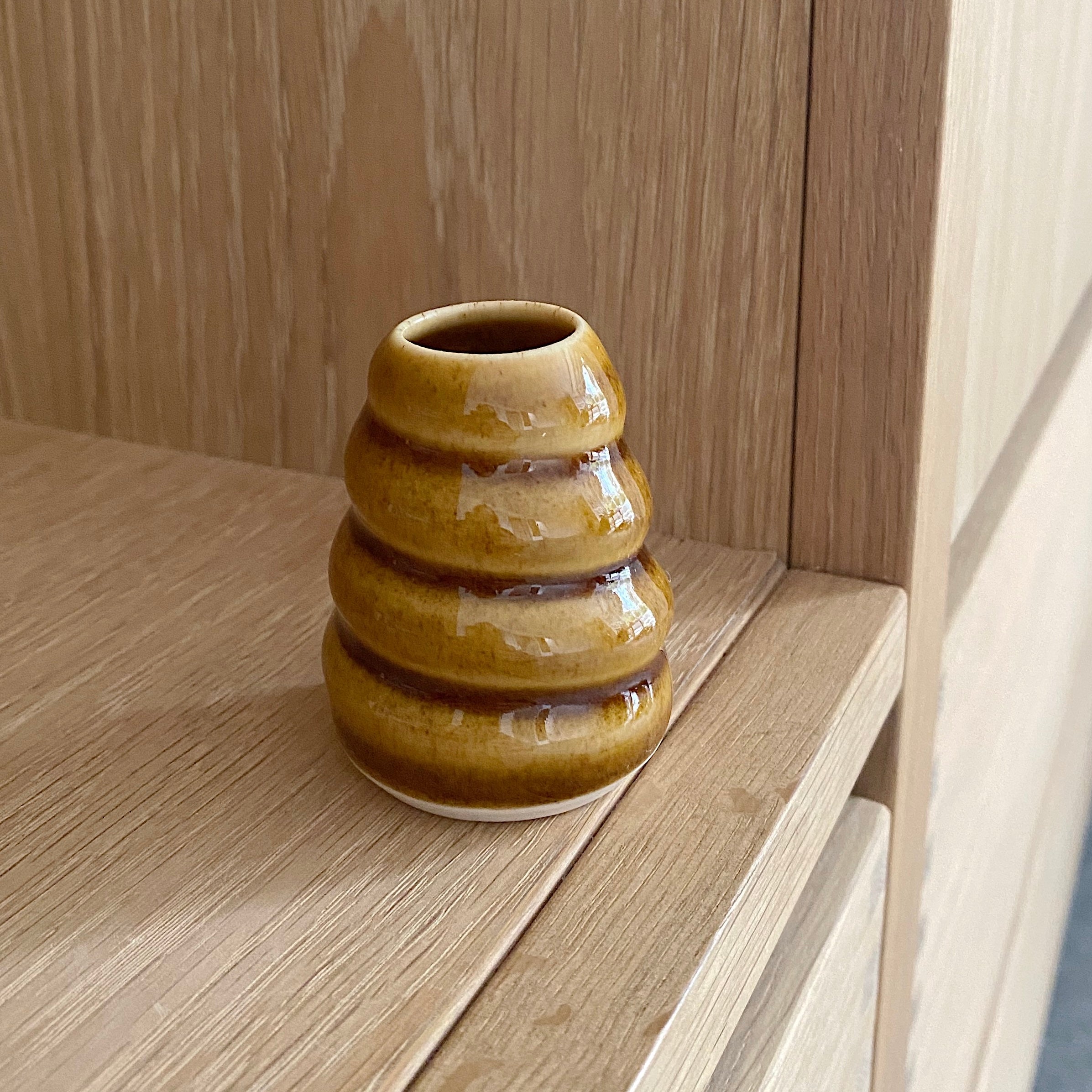 lille haandlavet vase i smuk gylden brun glasur. vasen har et snoet spiraldesign rundt om vasen