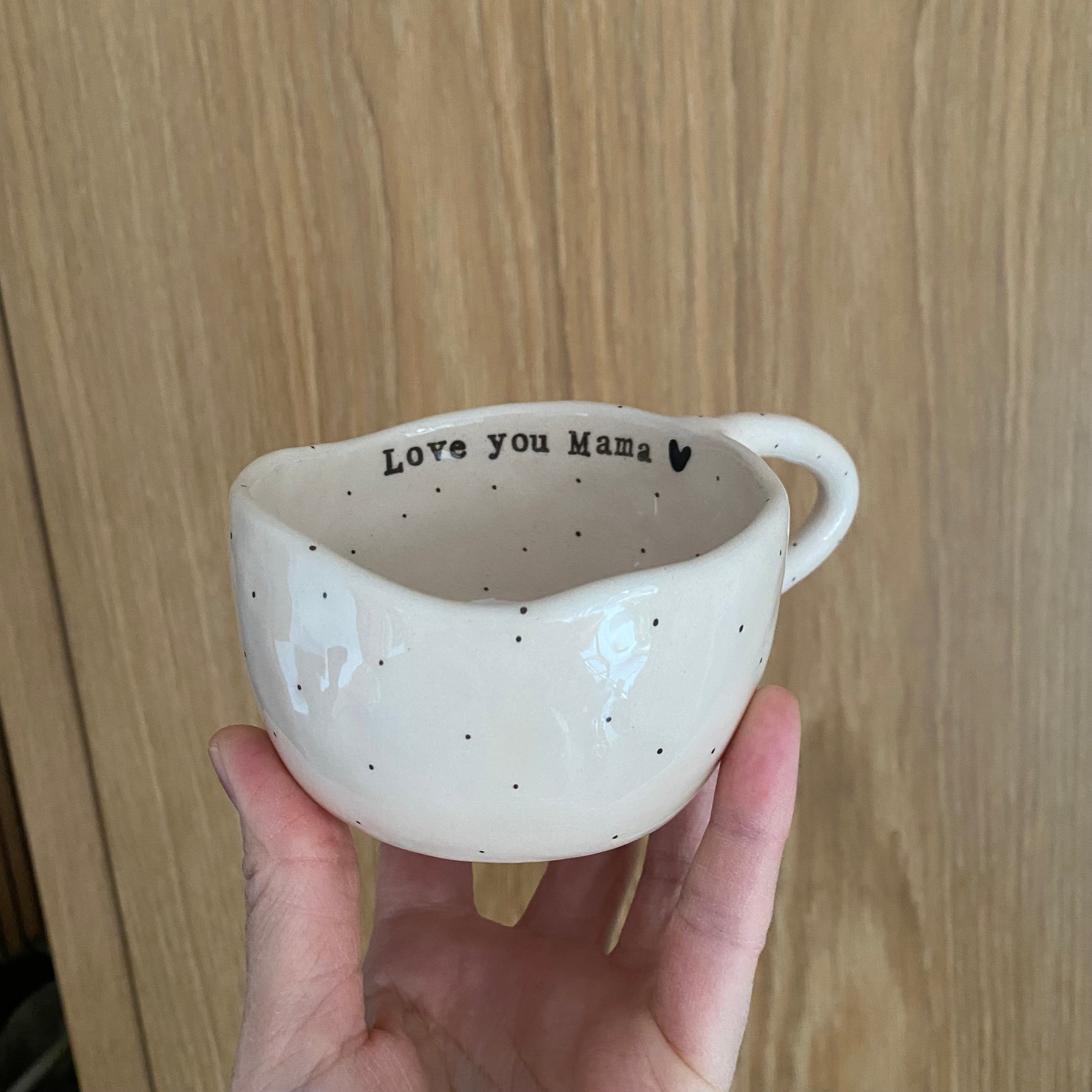 Håndlavet kop med hank og tekst “Love you Mama, to the moon and back” i nude keramik med sorte prikker
