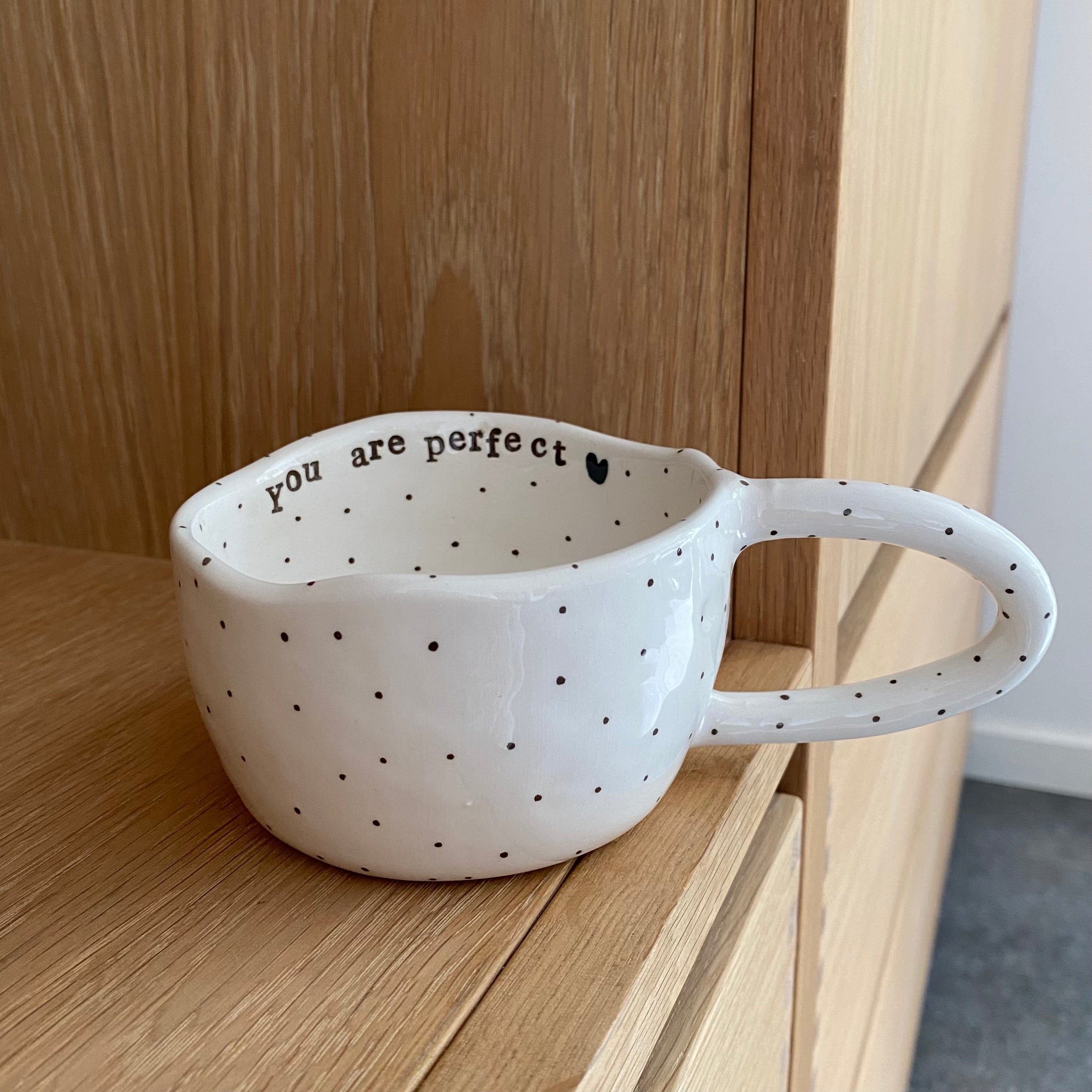 Håndlavet kop med hank og teksten “You are perfect” og teksten Love i bunden. koppen er i hvid keramik med sorte prikker