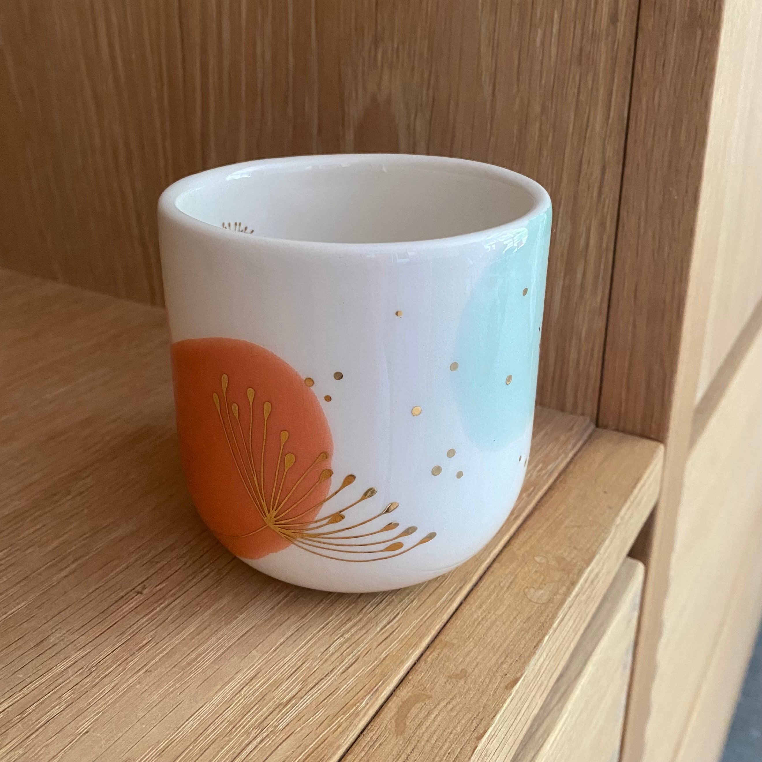 Håndlavet lattekop i keramik med orange og guldillustration – Marinski Dandelion