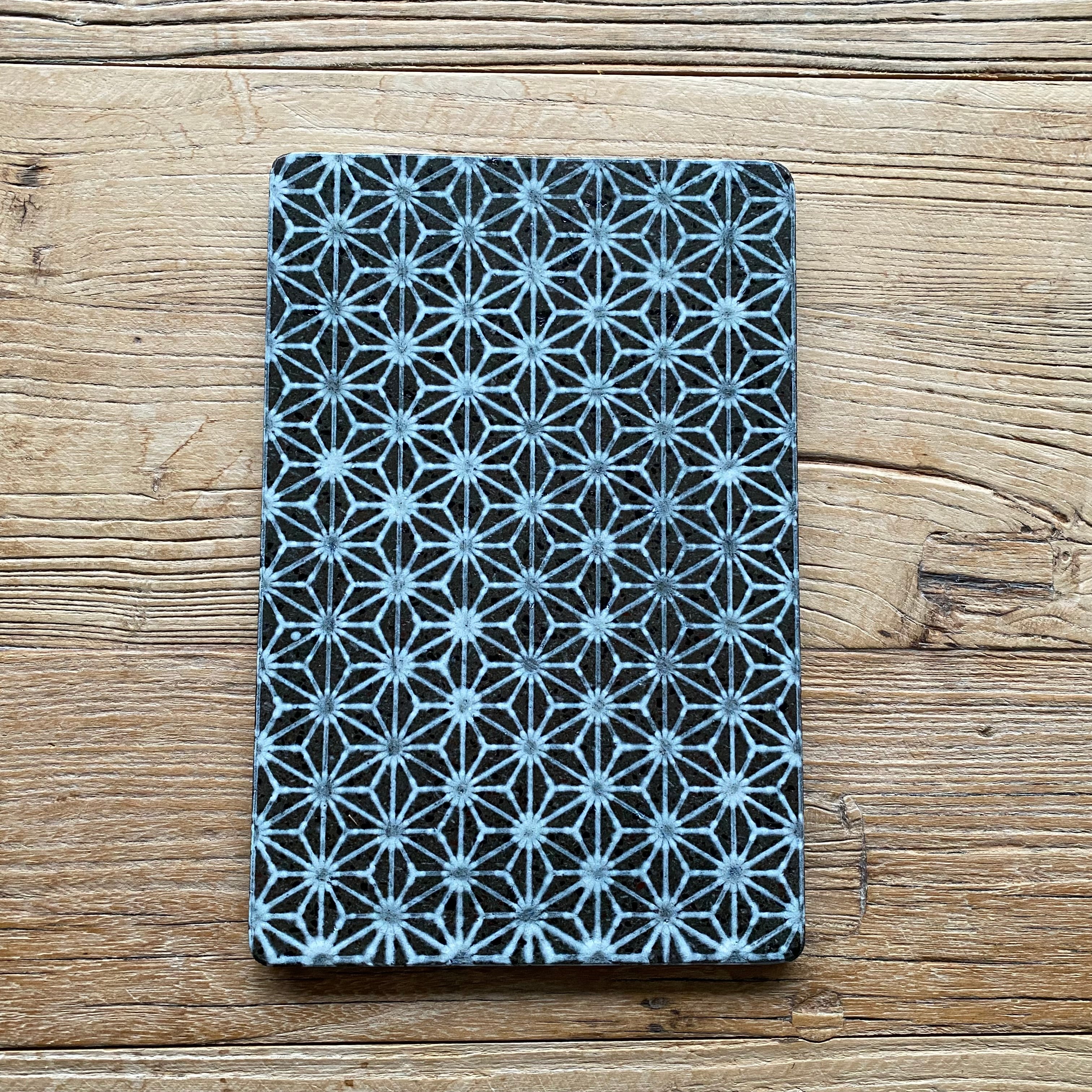 Lavastensbræt i mørk lavasten med hvidt stjernemønster brugt til servering og borddækning