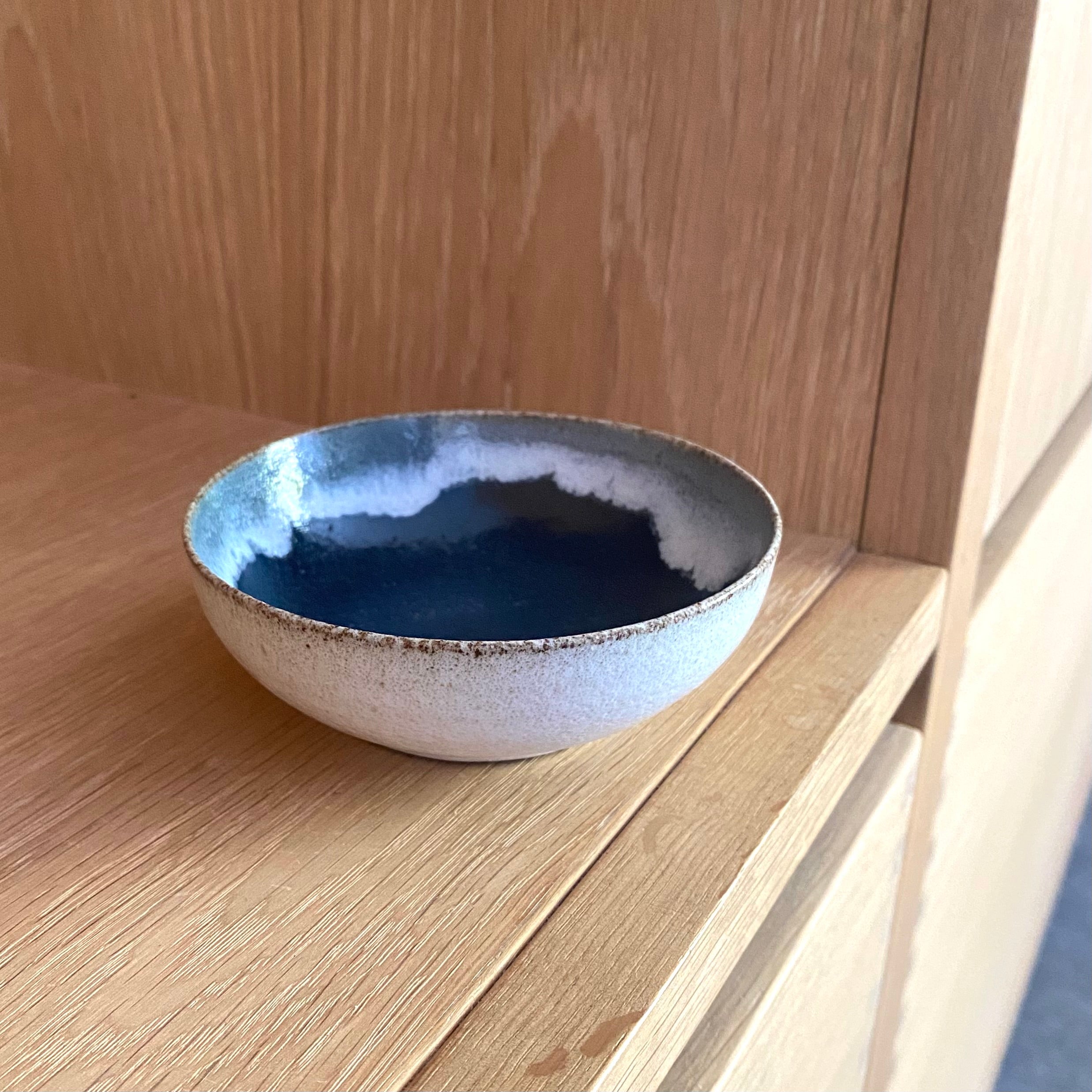 Smuk lille keramikskål med dyb blå glasur indeni og cremehvid yderside