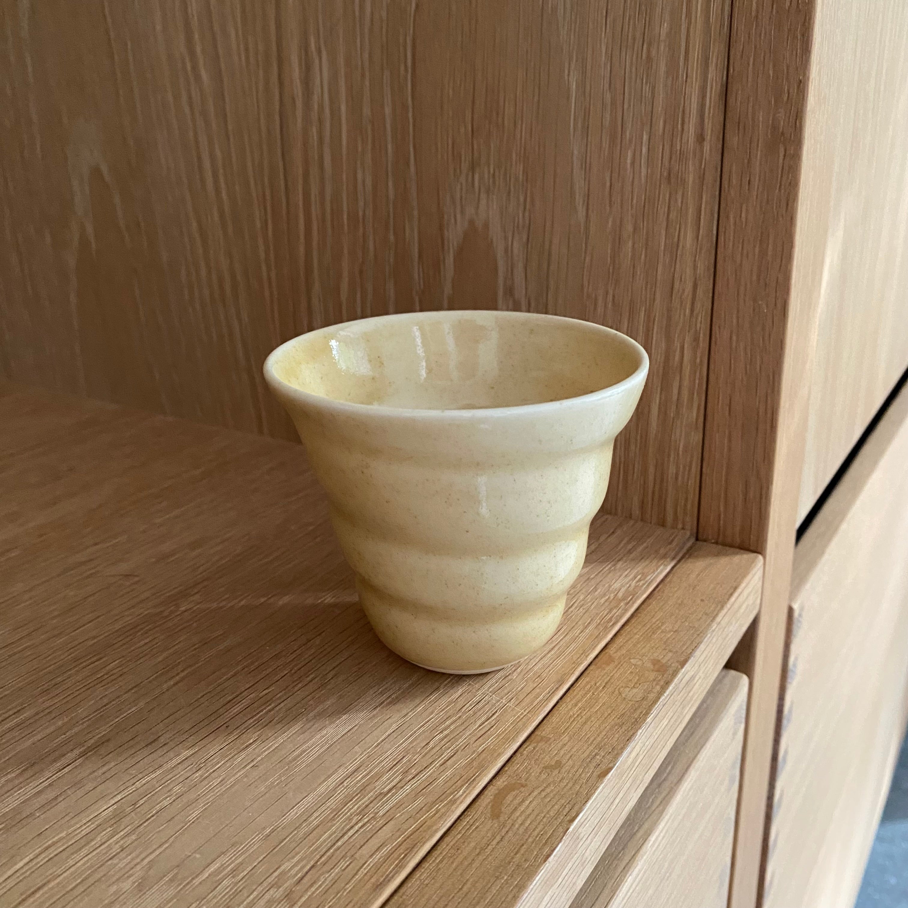 Håndlavet porcelænskop i svag gyldengul – cortado spiralkop fra Rikke Mangelsen.